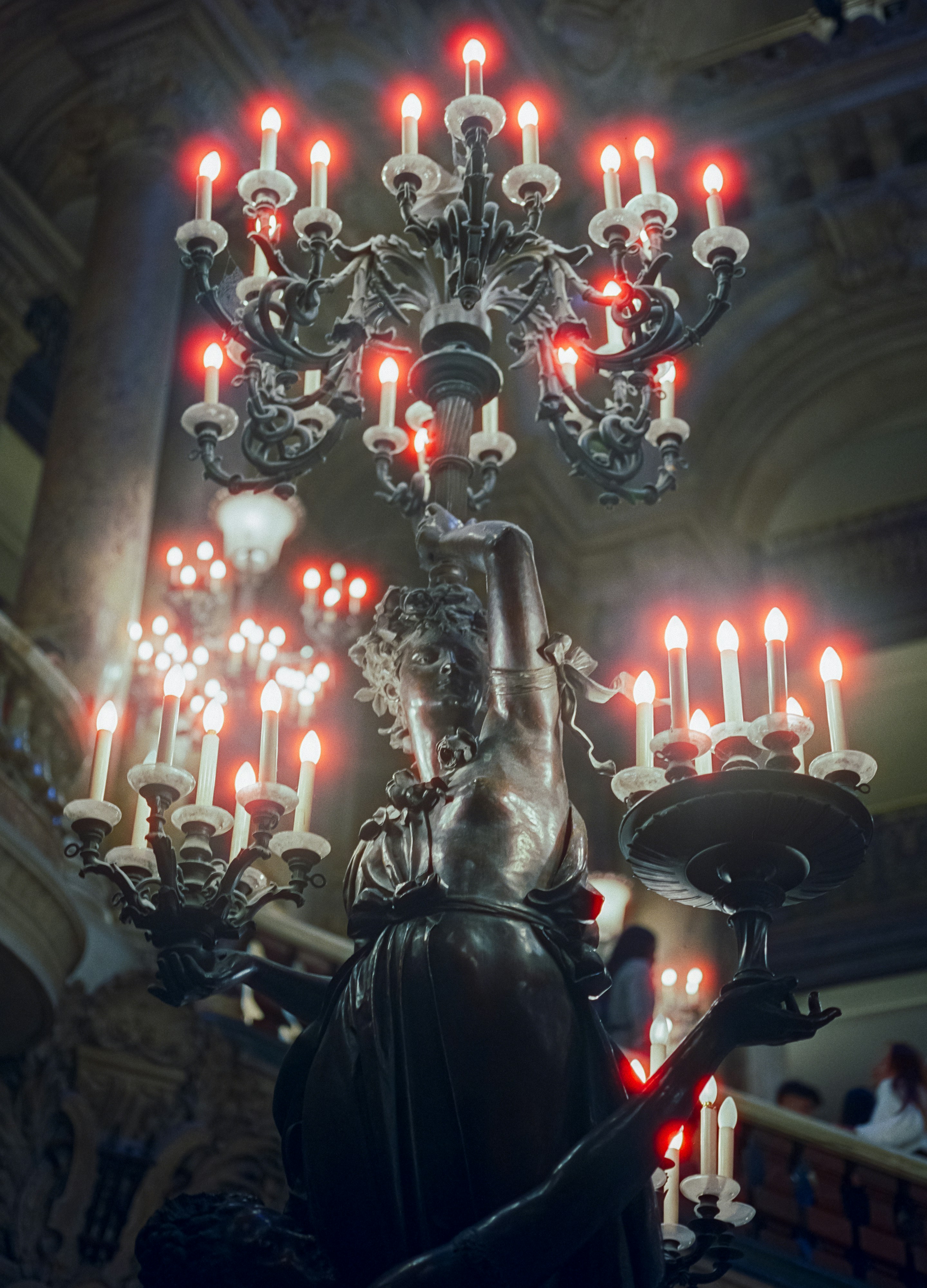 Ornate chandelier with glowing red lights and statue