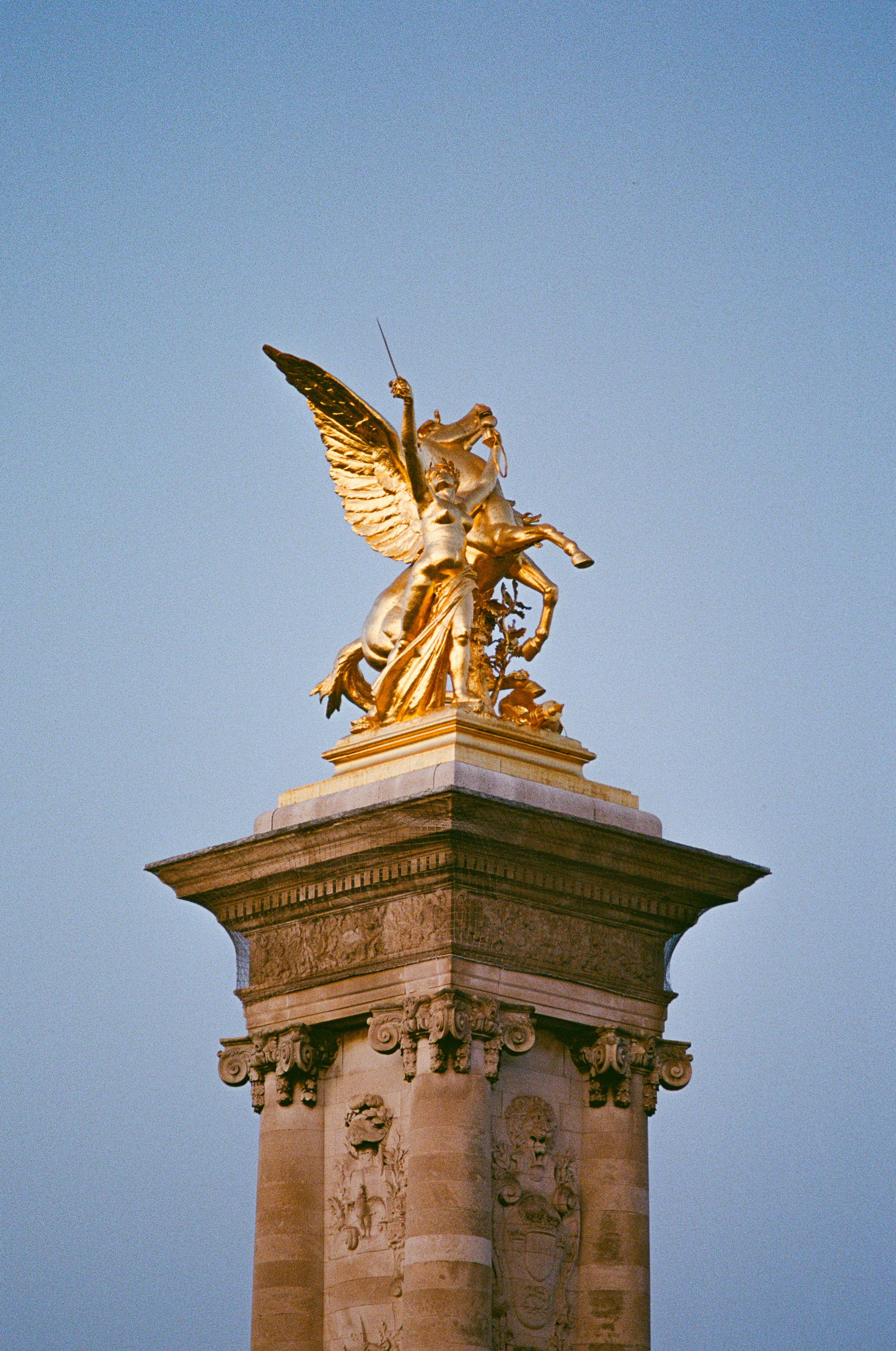 Golden statue of winged horse and rider on pedestal.