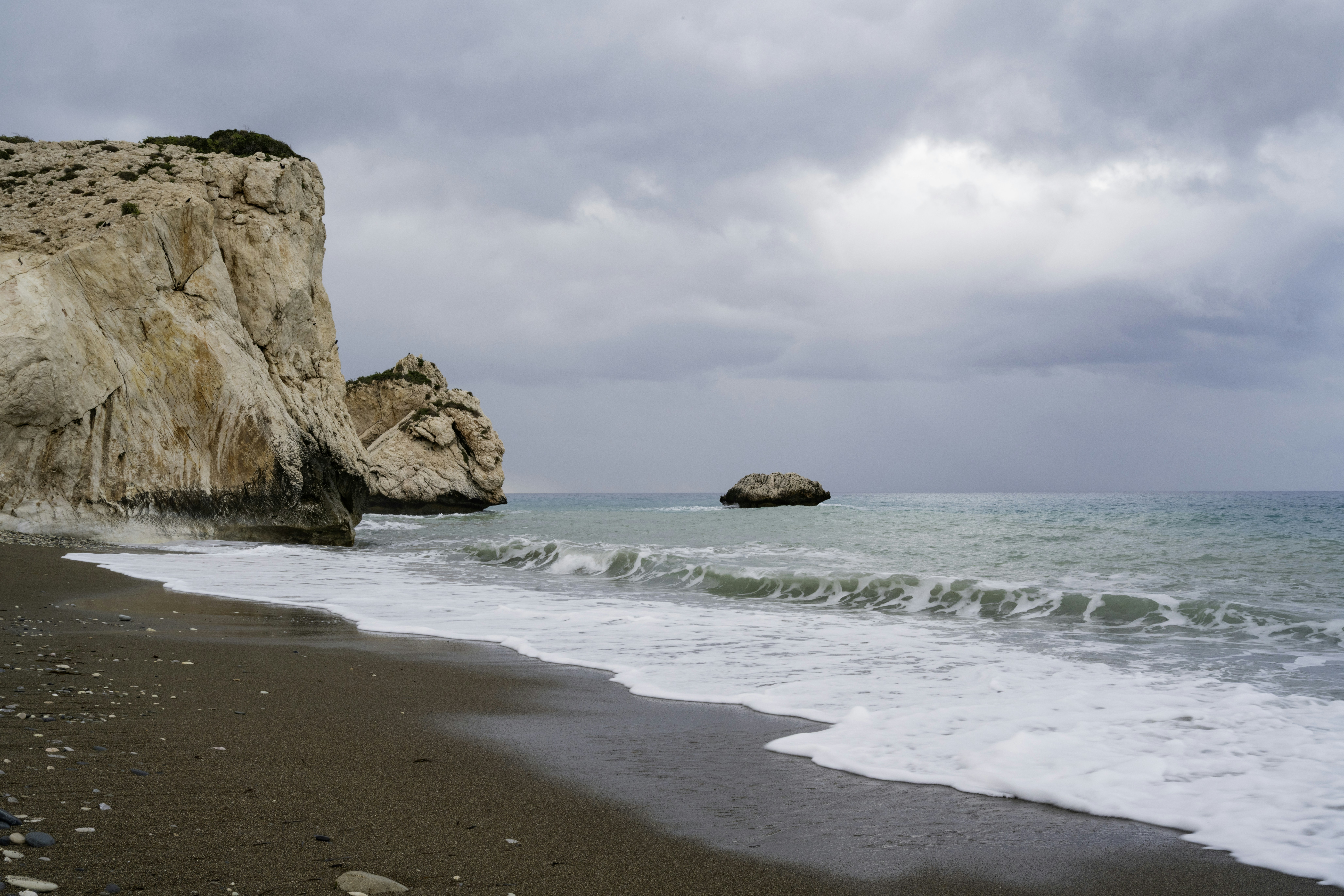 Waves crash on a rocky shore under cloudy skies