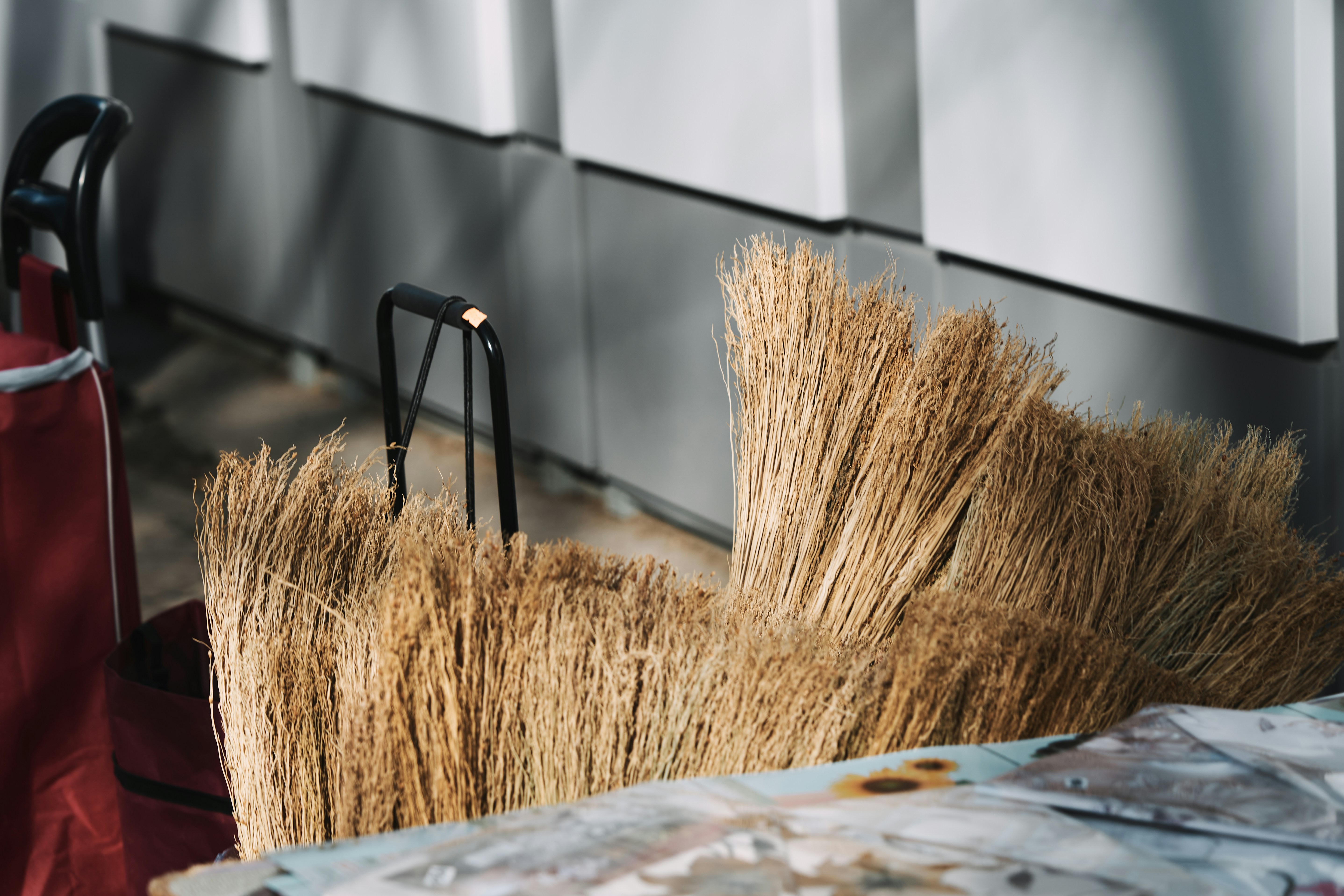 Broomsticks leaning against a wall with a red bag.