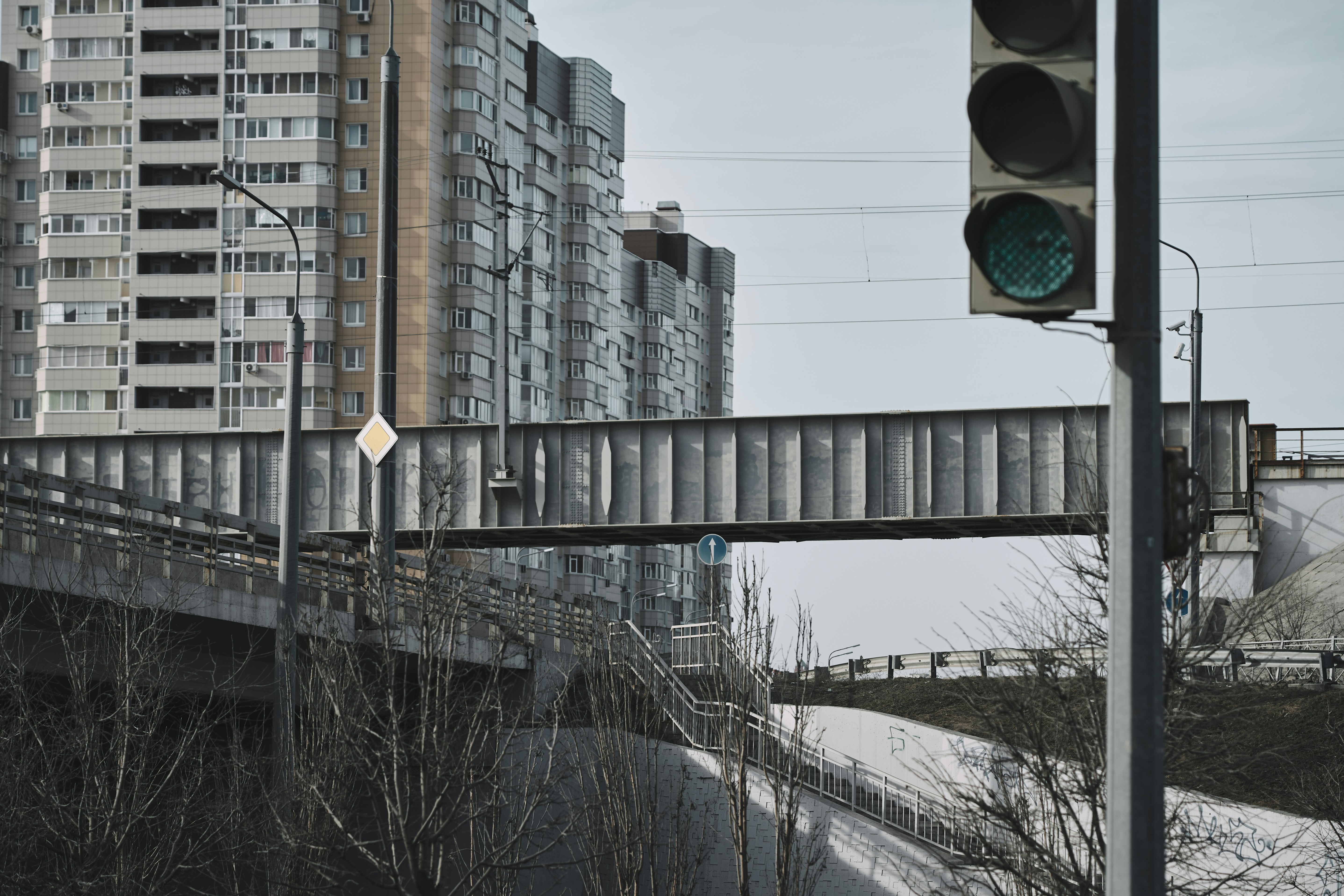 Un pont piétonnier enjambe une route avec des bâtiments derrière.