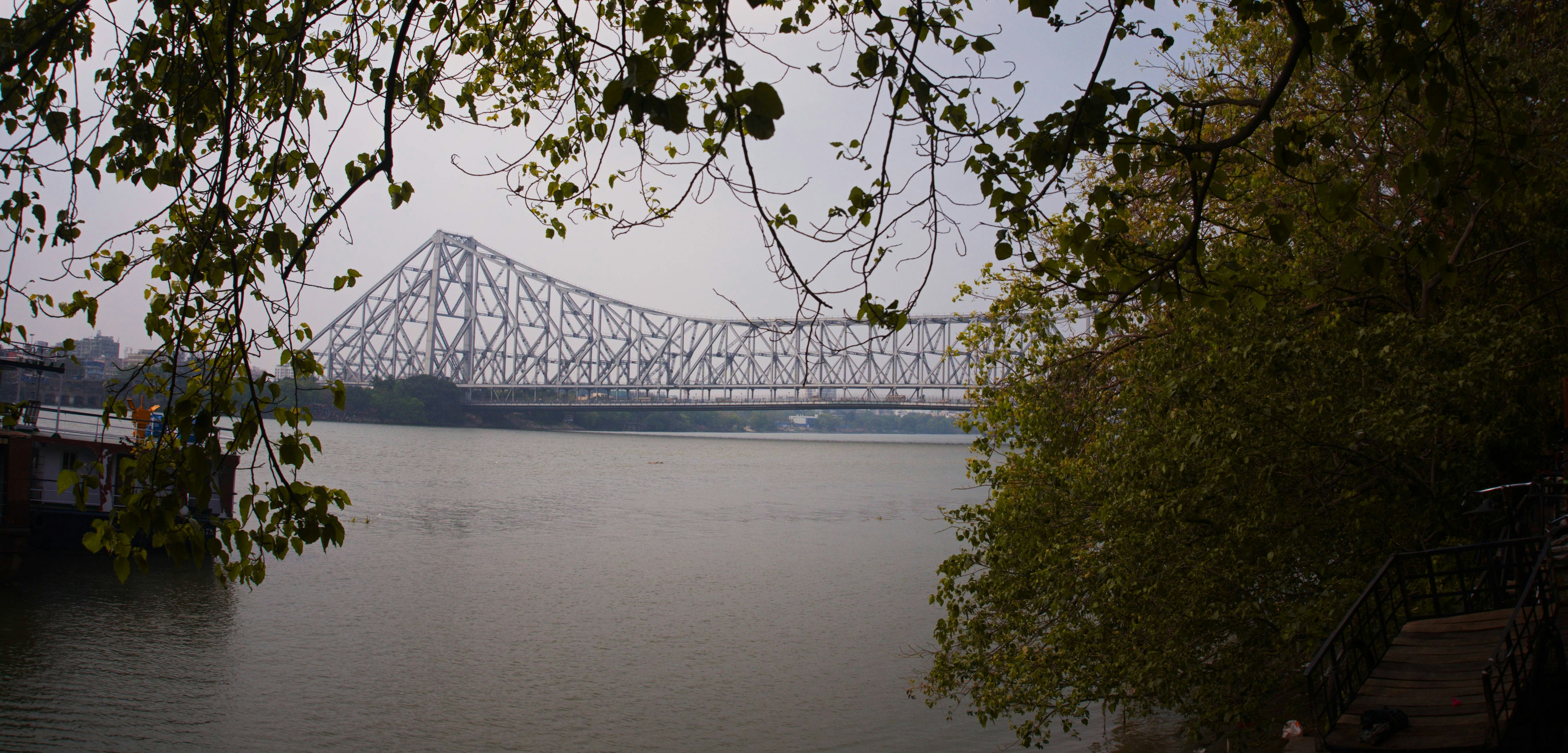 전경에 나무가 있는 후글리 강 위의 하우라 다리