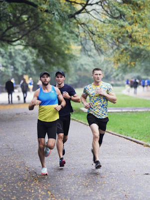 Three men jogging on a park path