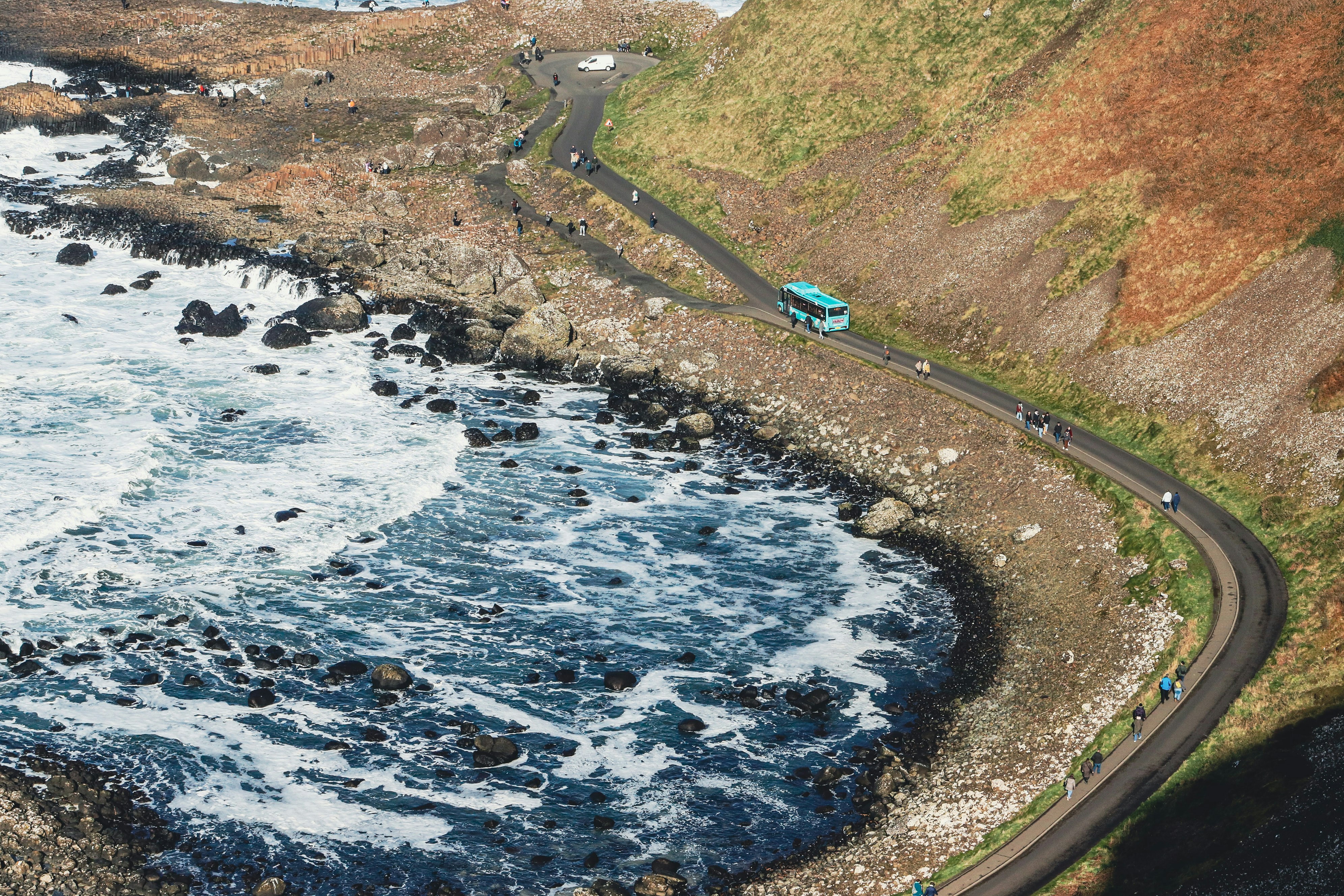 ターコイズ色のバスは海沿いの曲がりくねった海岸沿いの道路を走っています。