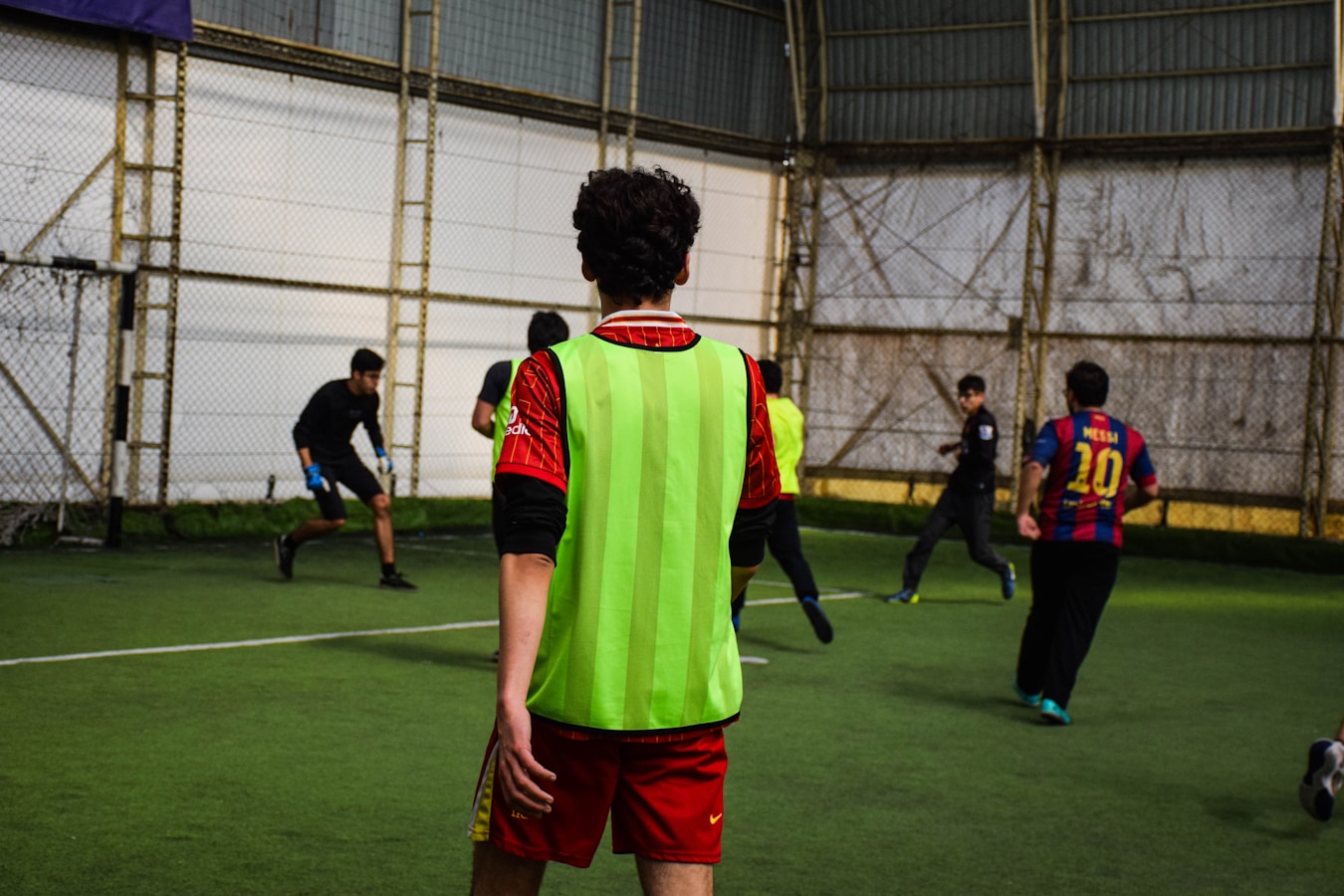 Jóvenes jugando al fútbol 5 en una cancha con césped sintético