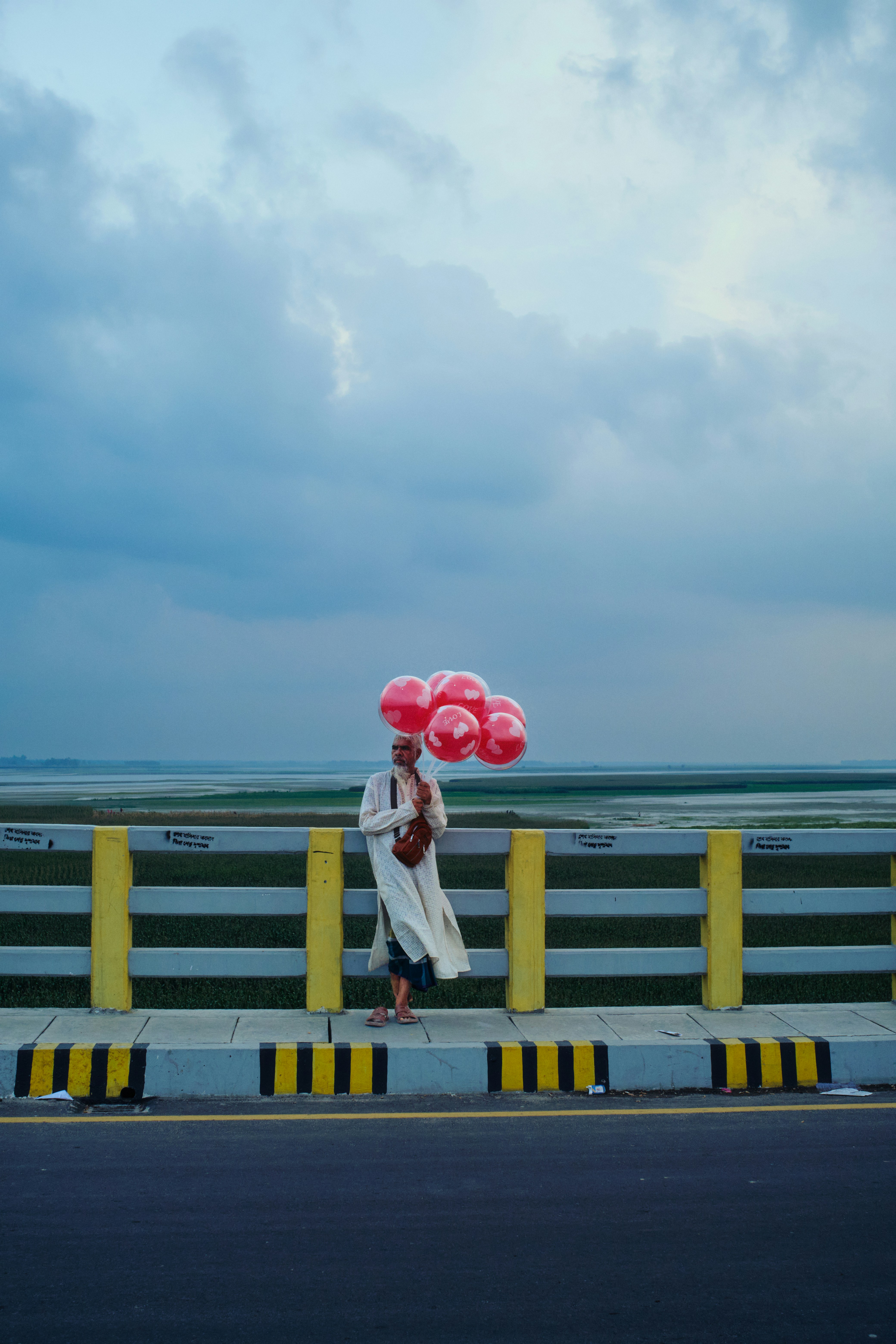 Person holding red balloons on a bridge