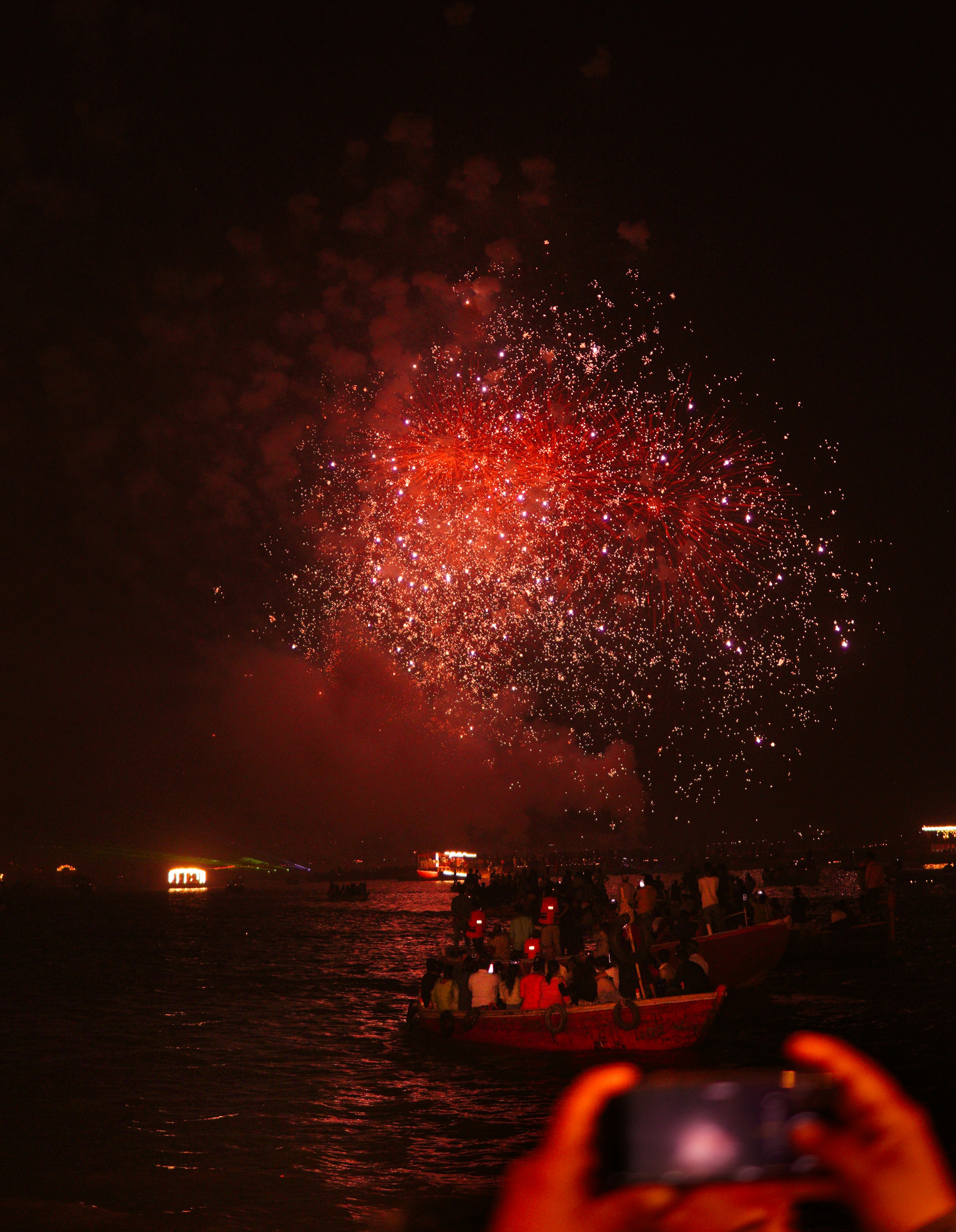 Feuerwerk explodiert über einem mit Menschen gefüllten Boot.
