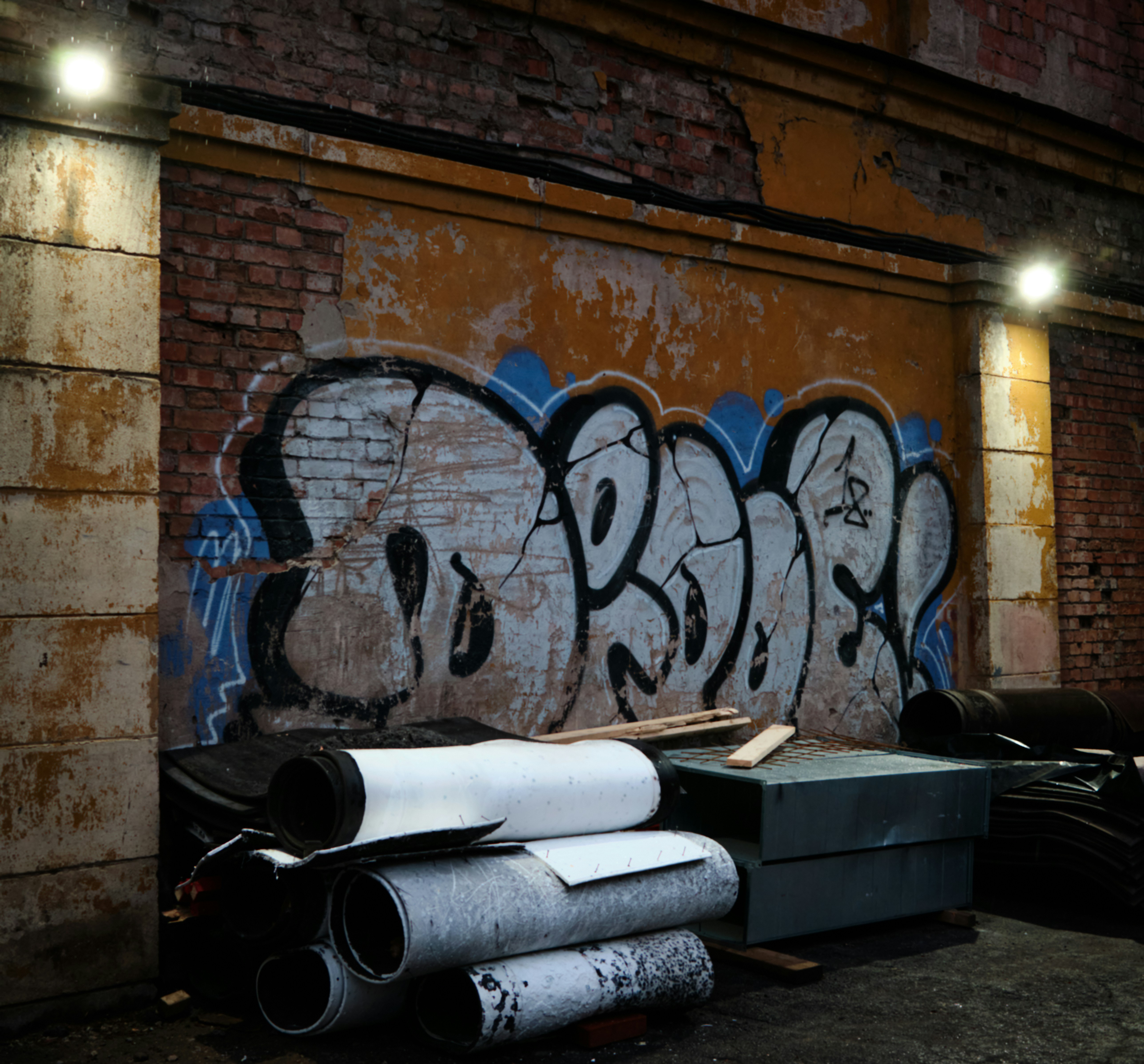 Graffiti on a brick wall with stacked materials.
