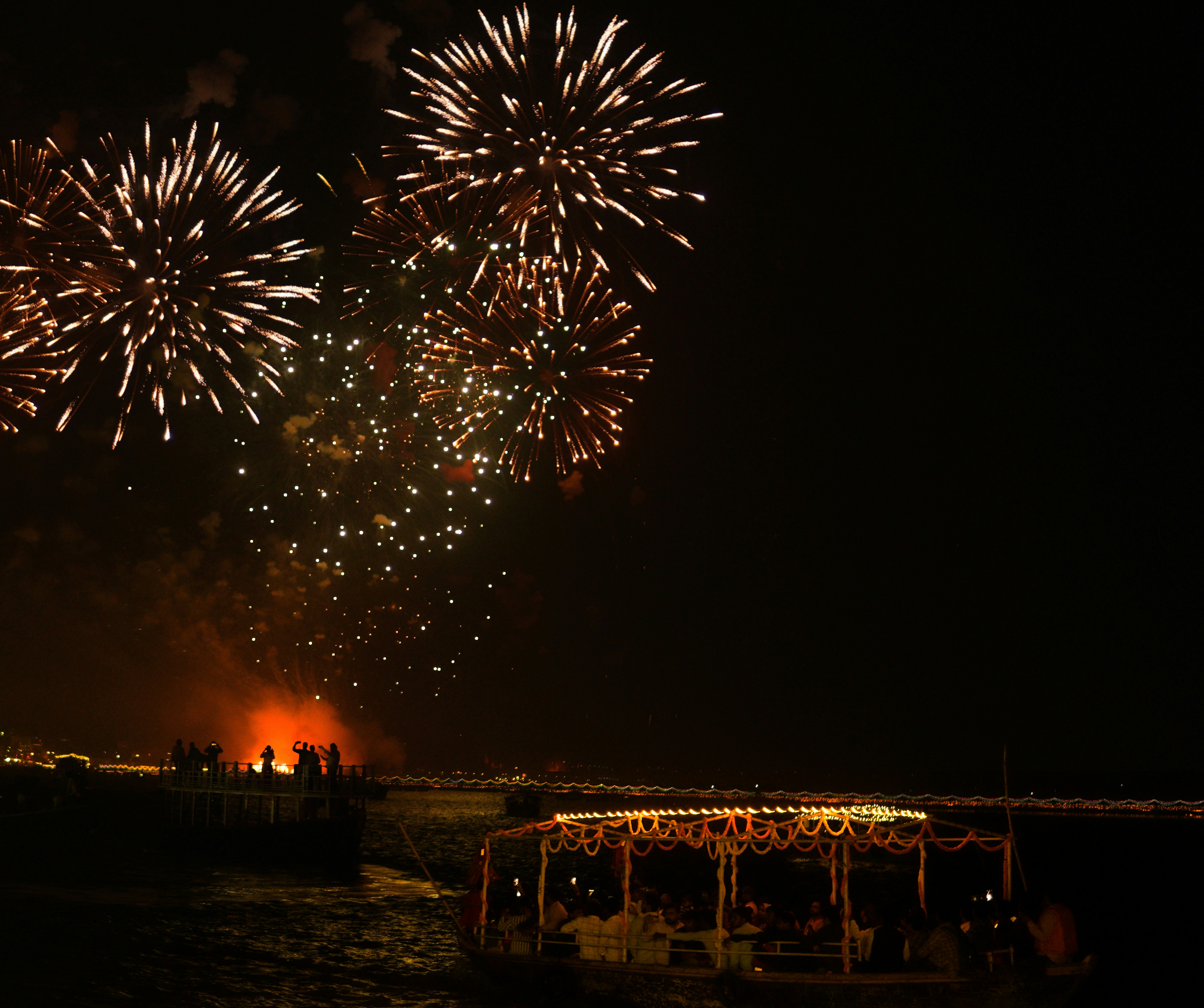 Feuerwerk explodiert über einem dunklen Himmel über einem Strandpavillon.
