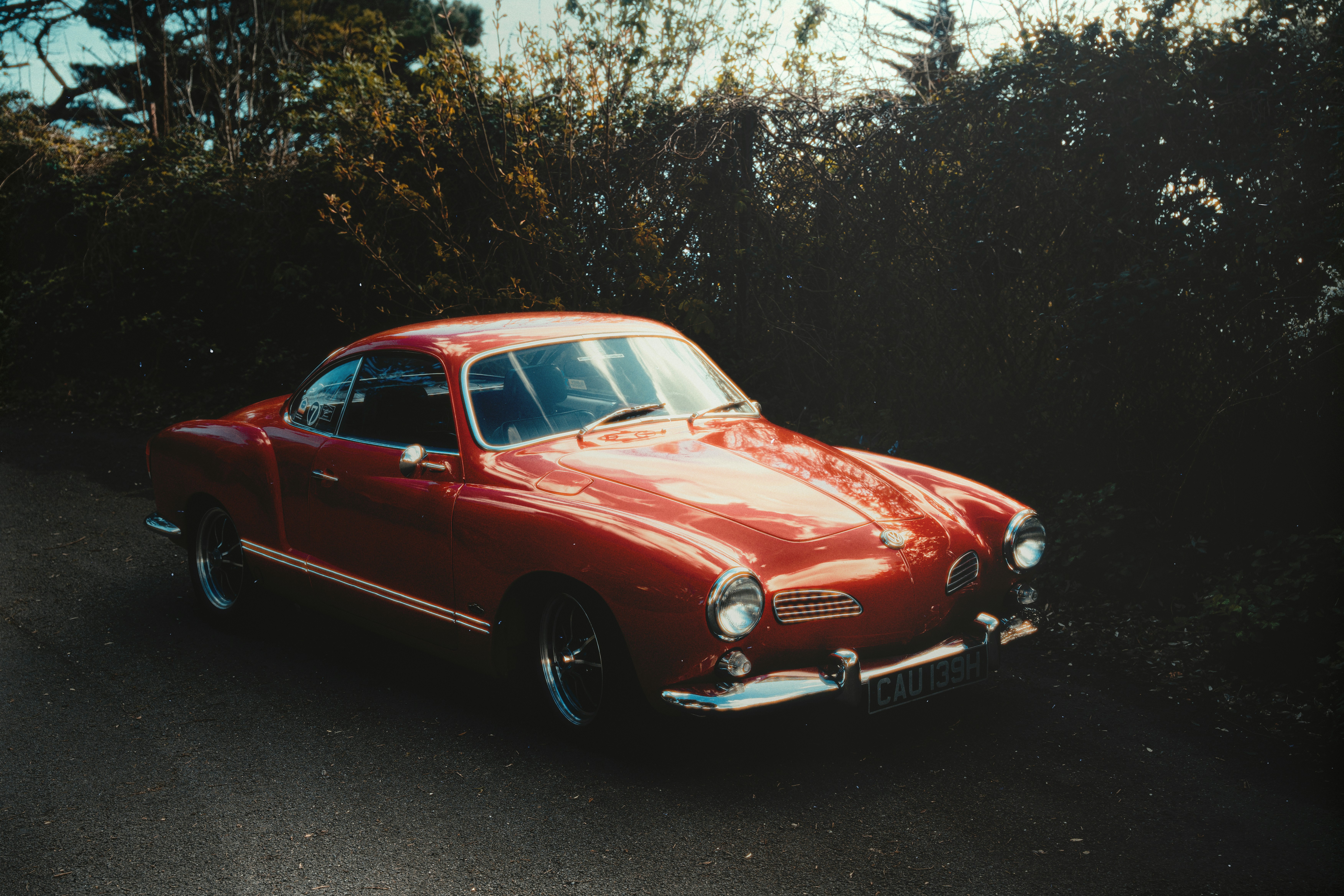 A vintage red car parked on a dirt road.