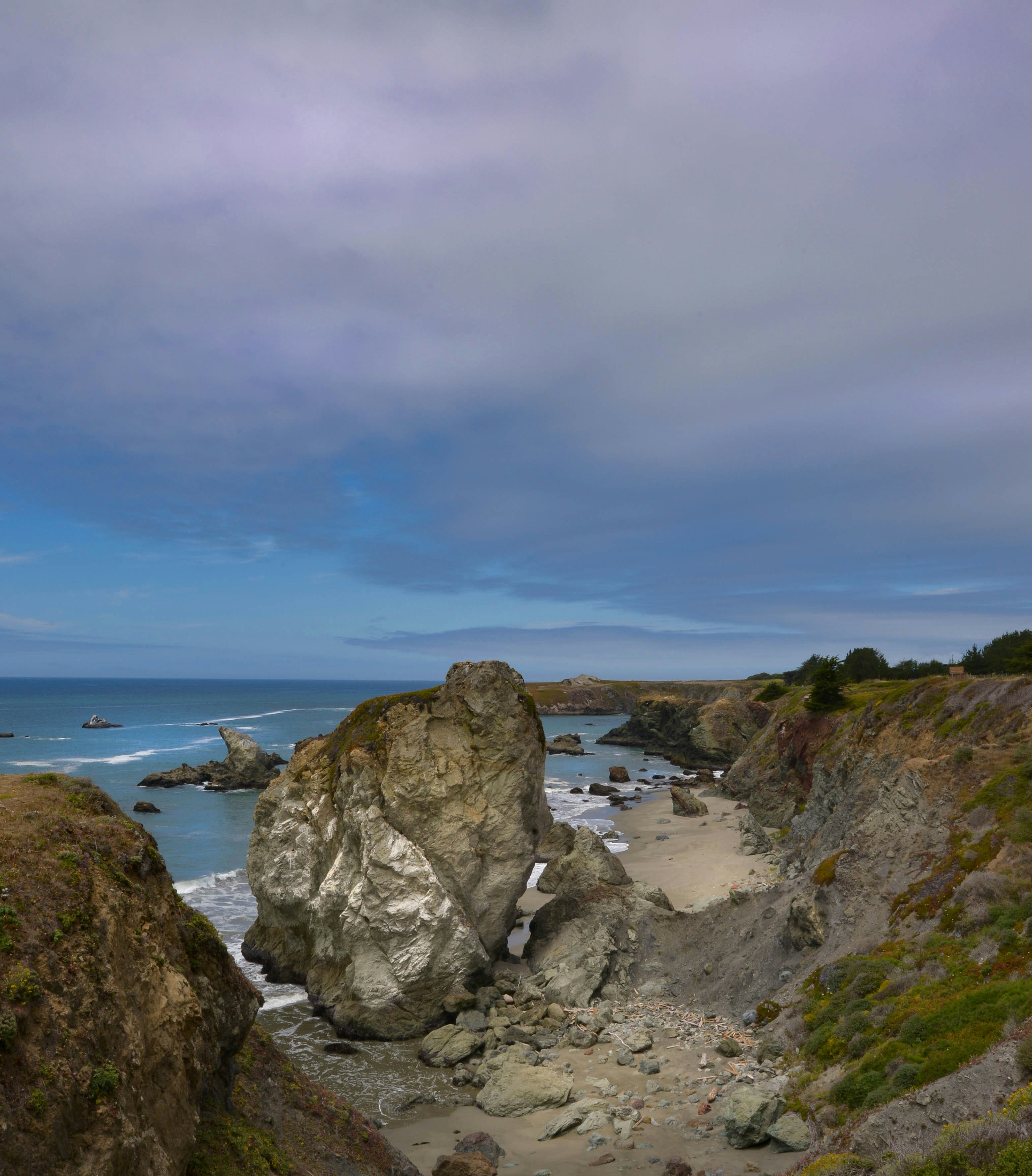 Rocky coastline with crashing waves under a cloudy sky