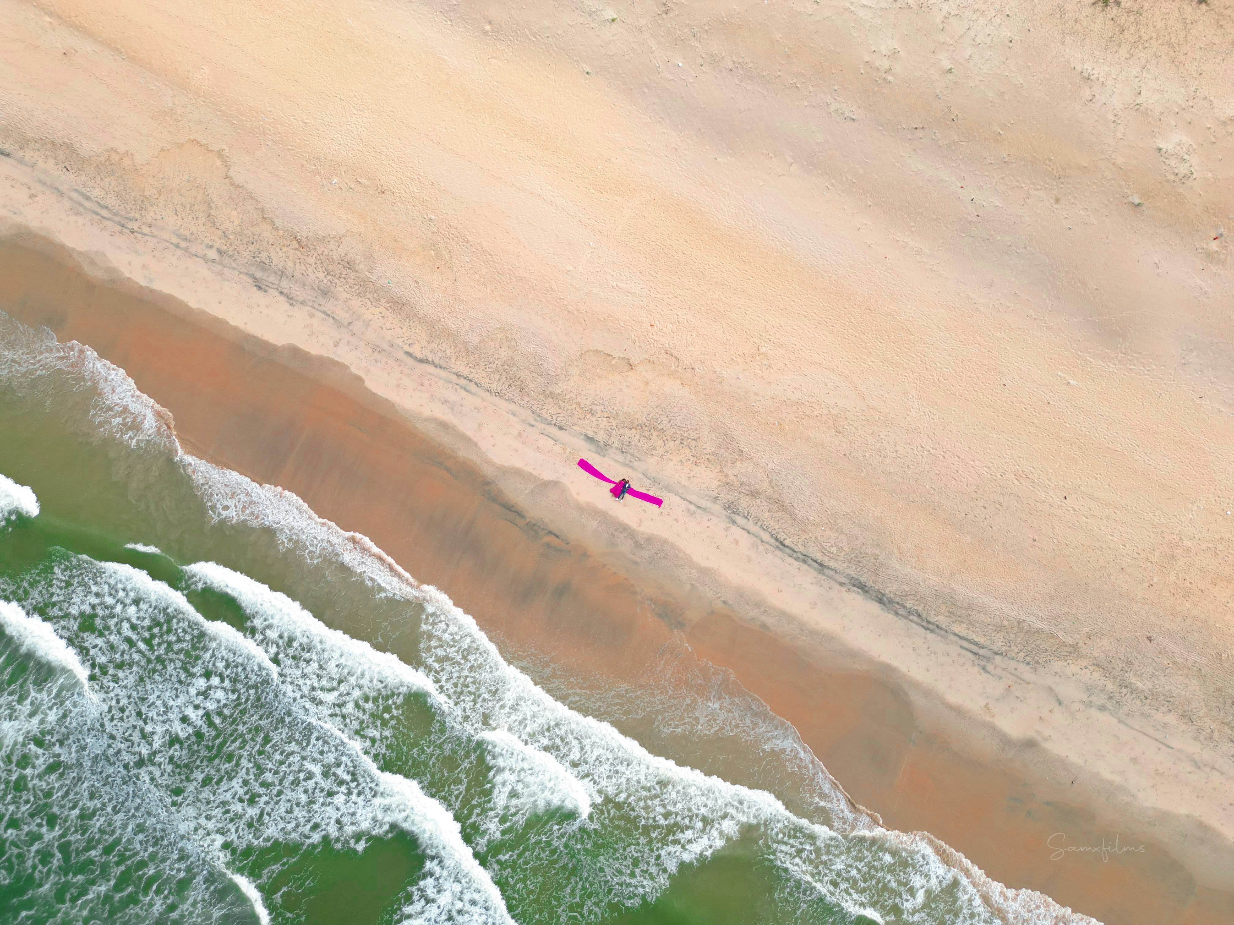 Person, die an einem Sandstrand in der Nähe der Meereswellen sonnt.