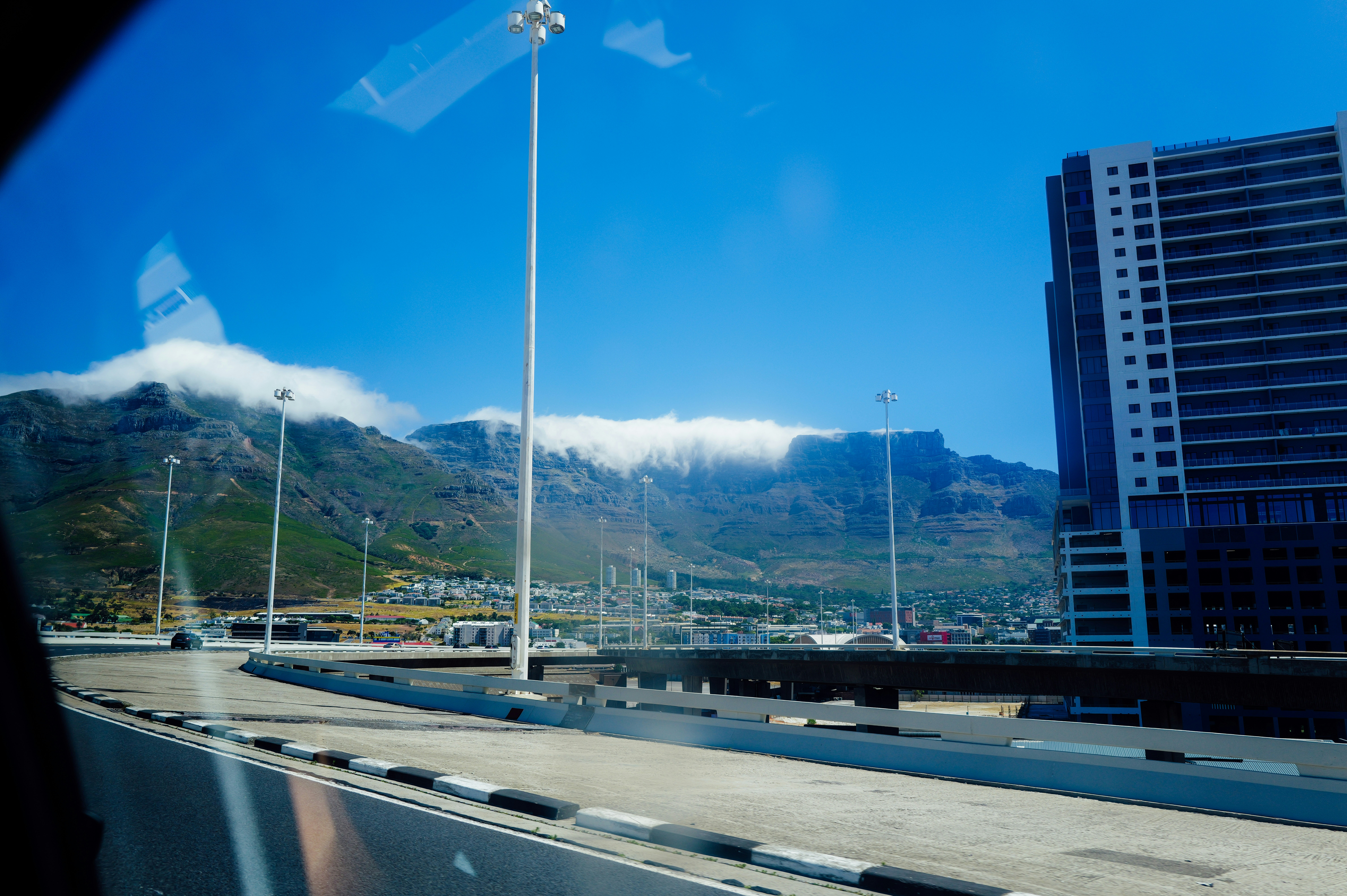 Modern buildings next to a mountain range under clouds.