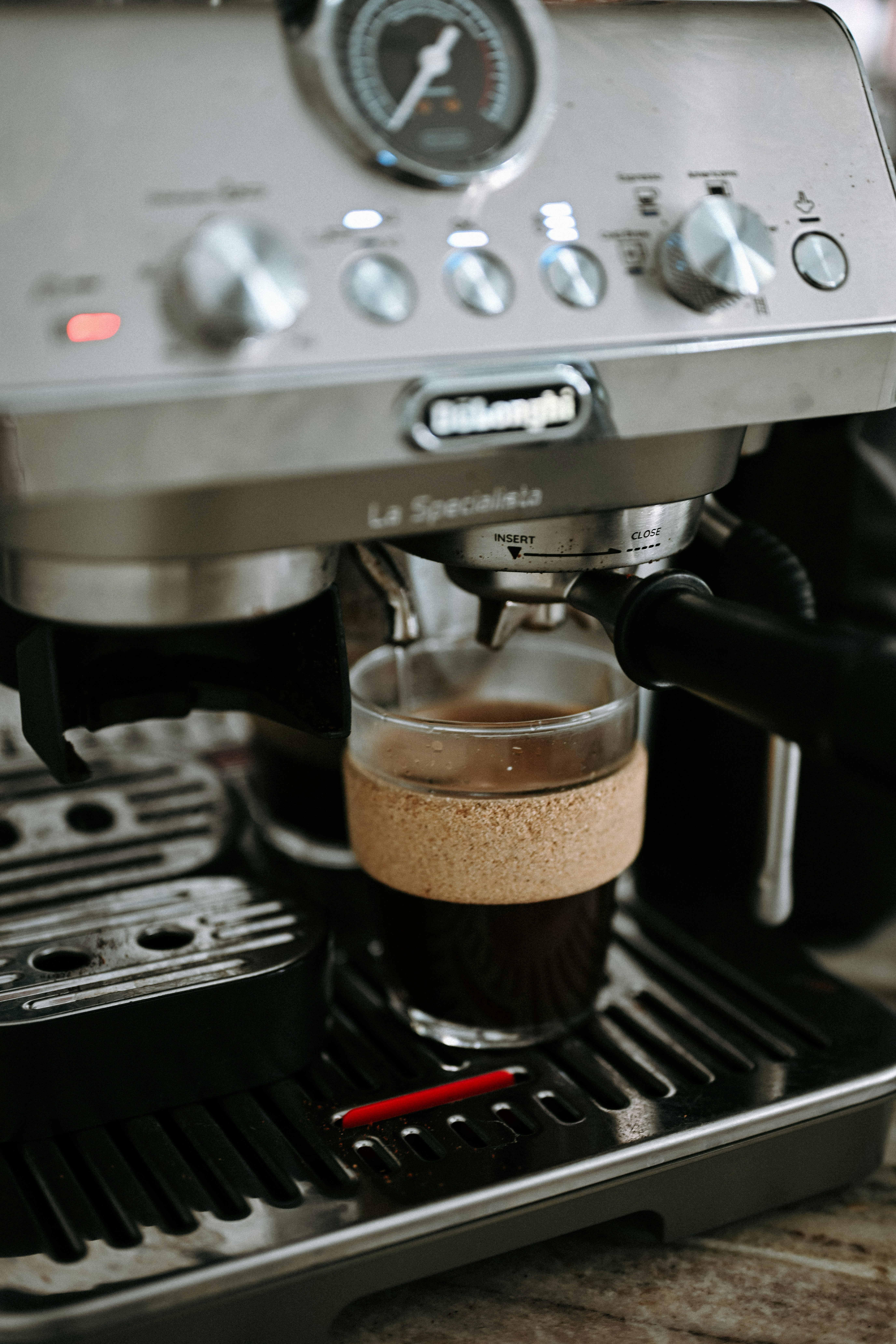 Máquina de espresso preparando café en una taza de cristal.