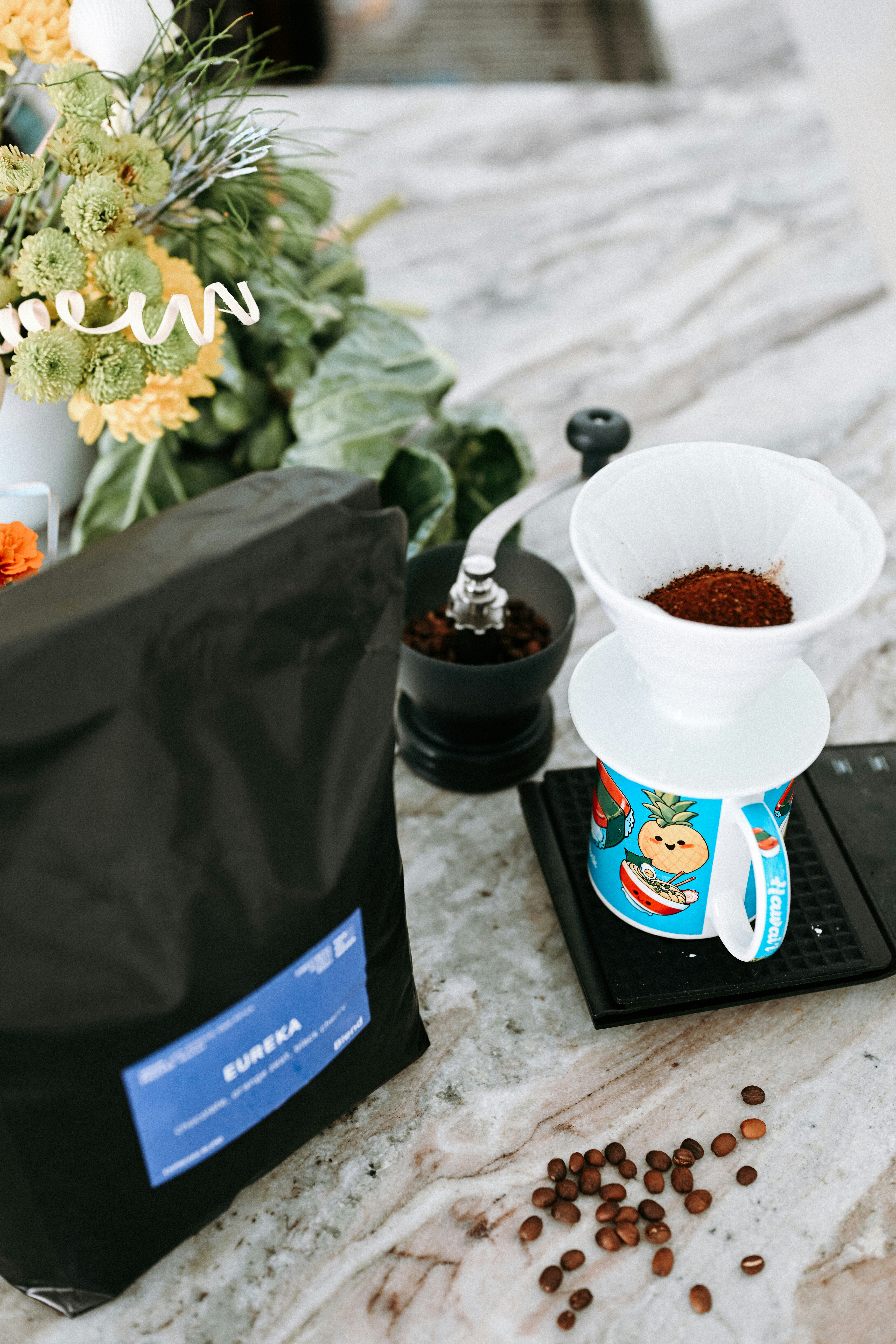 Coffee beans, grinder, and pour-over setup with flowers