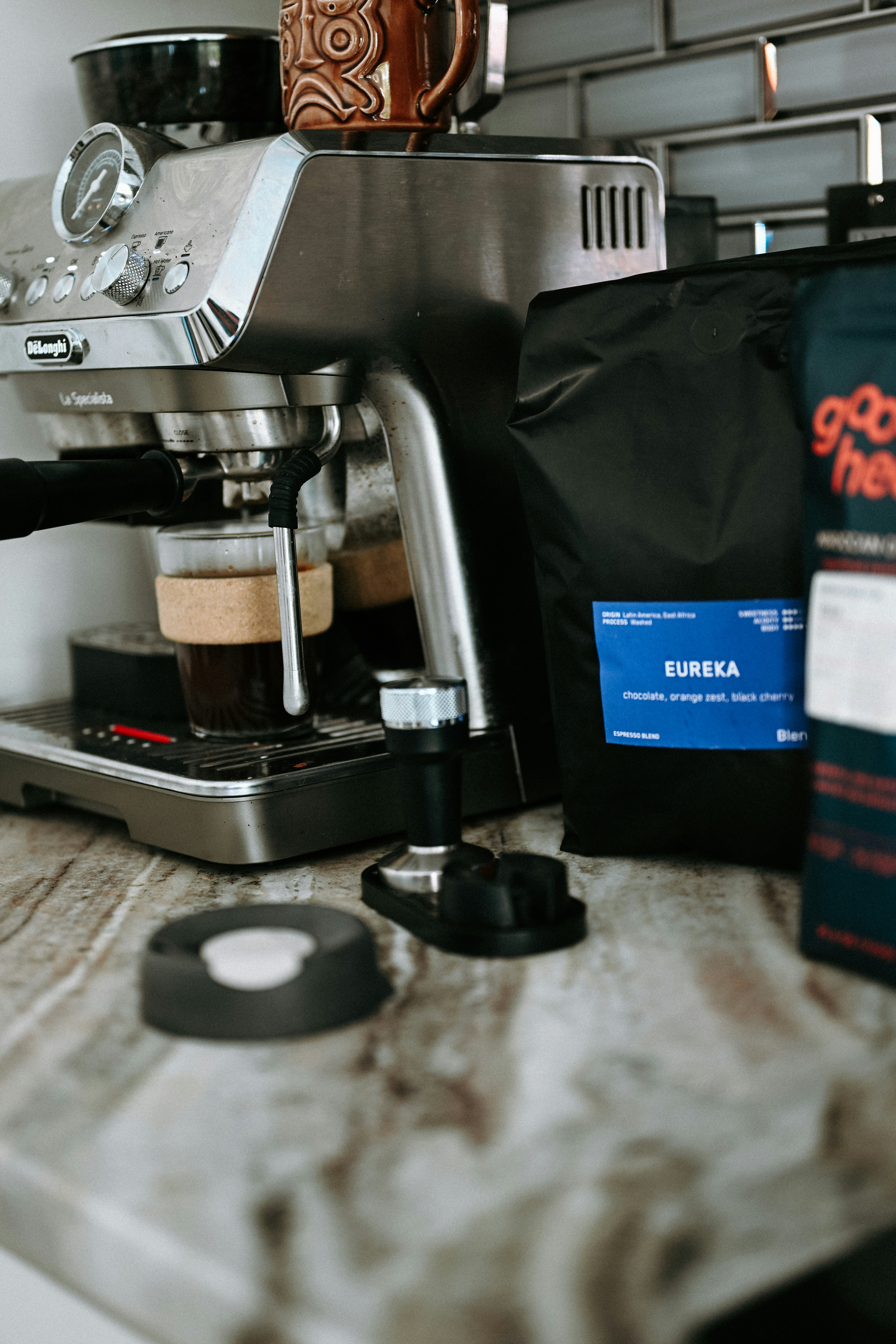 Espresso machine brewing coffee next to coffee beans.
