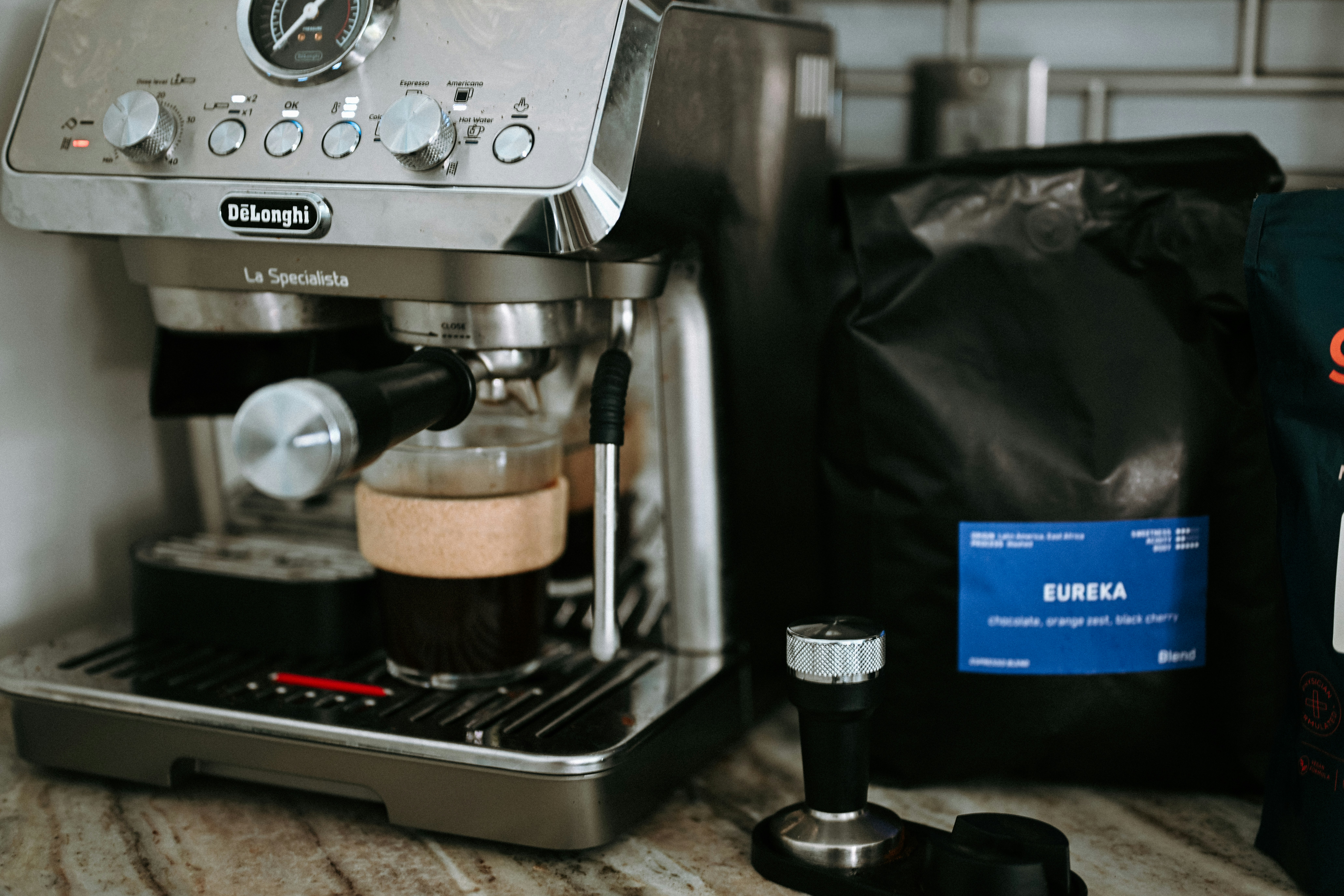 Espresso machine brewing coffee next to coffee bag.