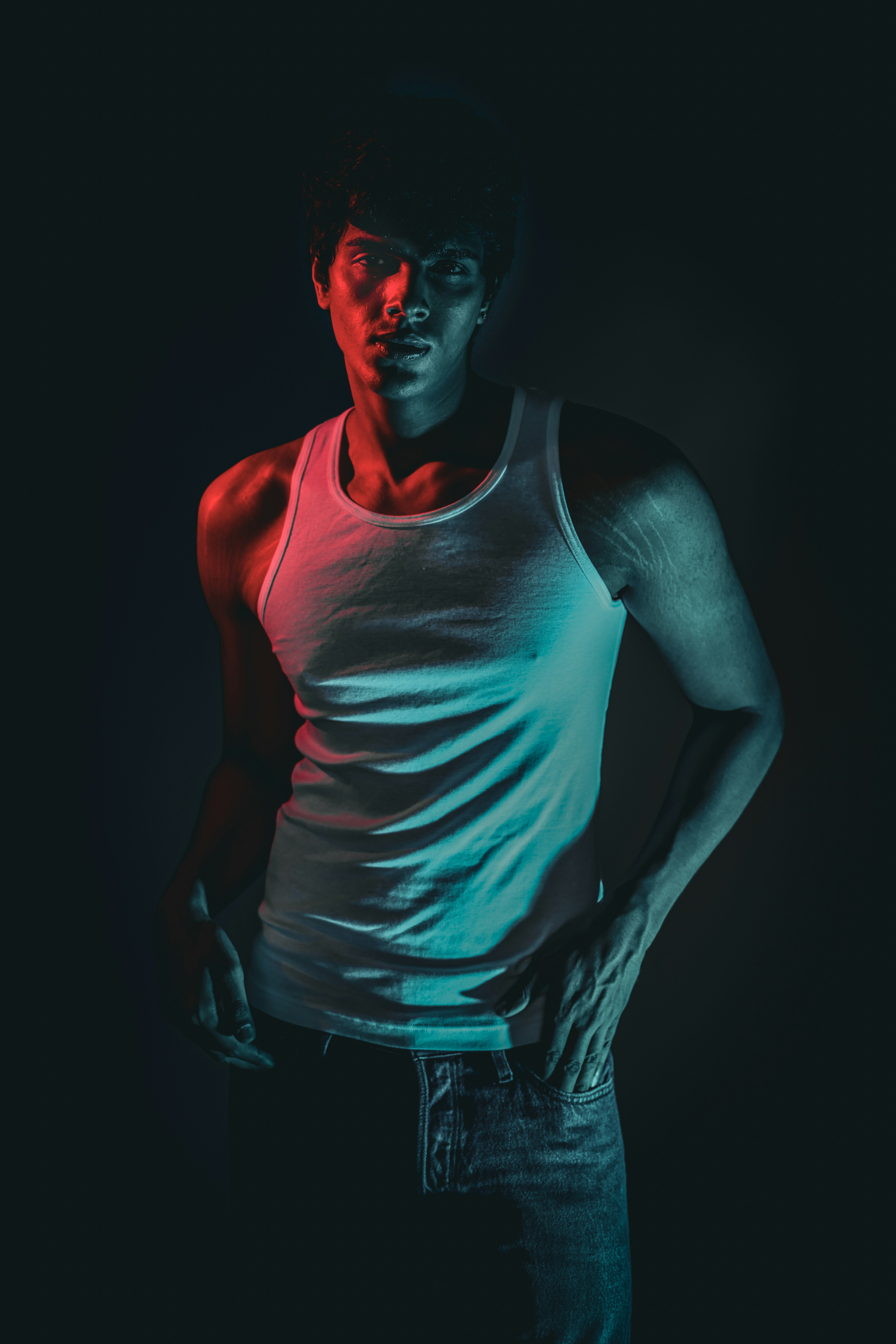 Man in tank top with red and blue lighting.