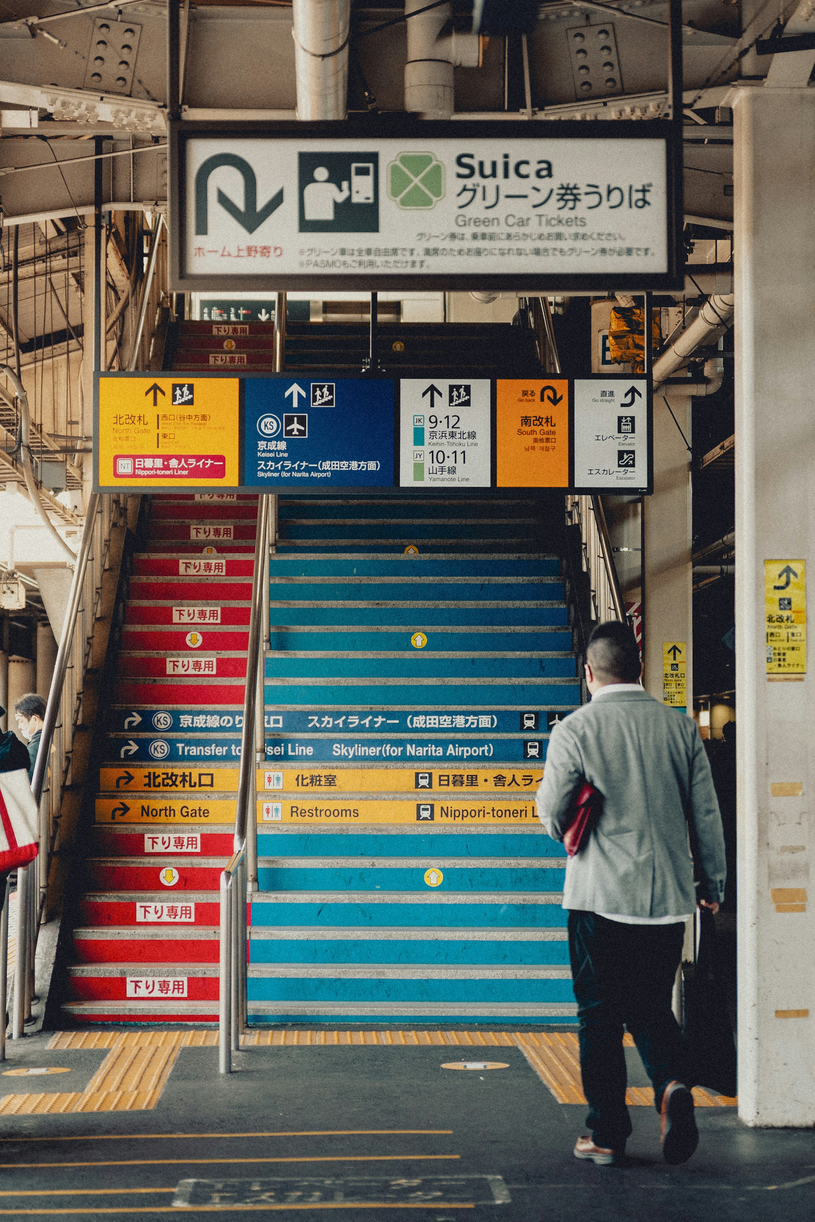 Man walks up colorful train station stairs with signs.