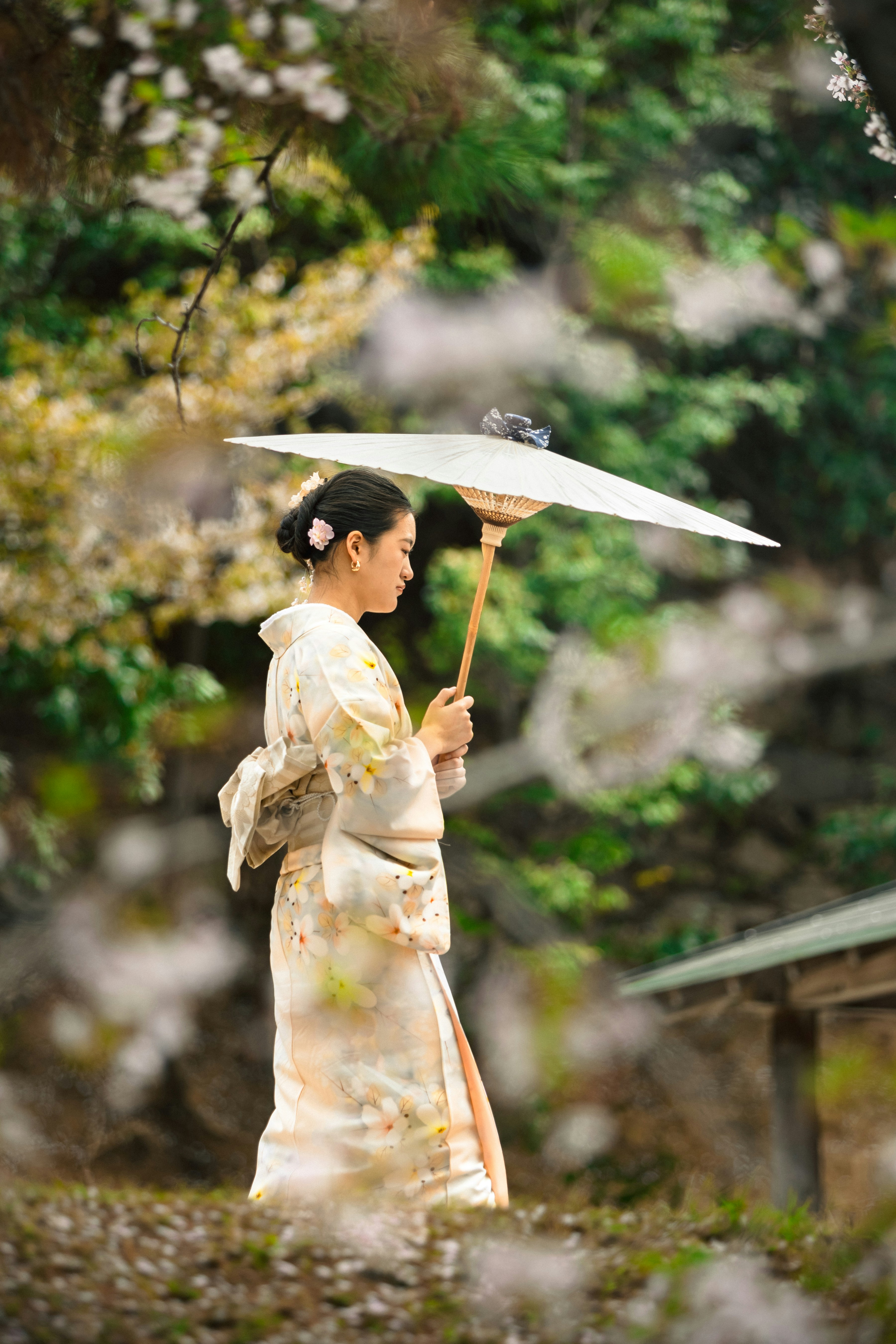Woman in kimono holding umbrella in a garden