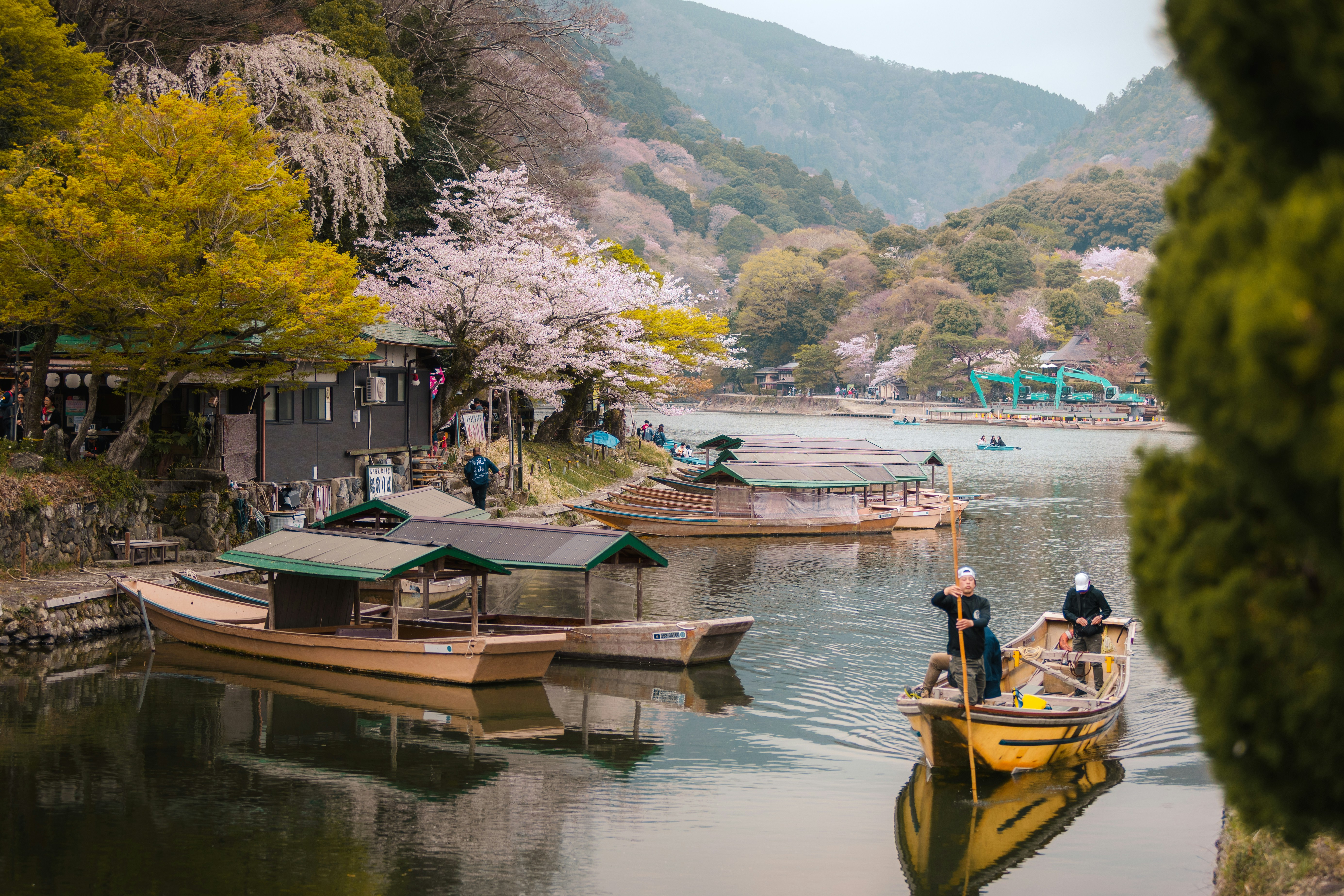 Boats on a lake with cherry blossoms and mountains