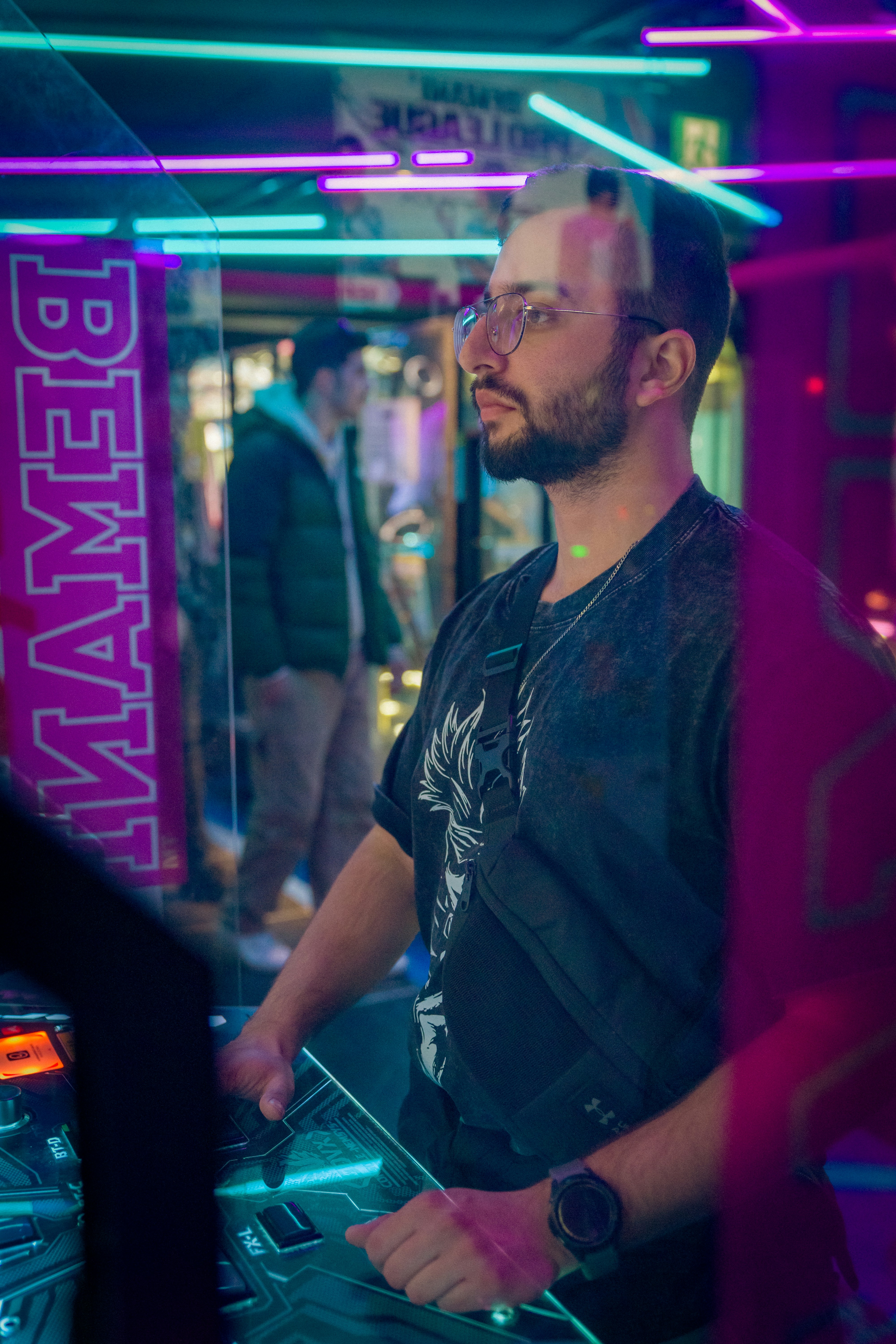 Man playing an arcade game with neon lights