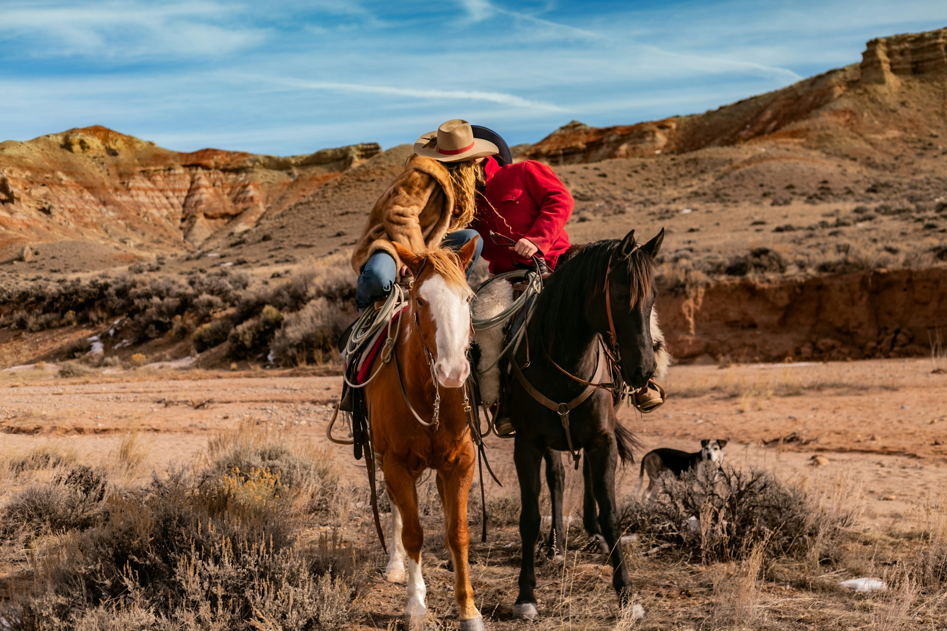 Cowgirl and cowboy share a kiss on horseback in the Wyoming badlands.