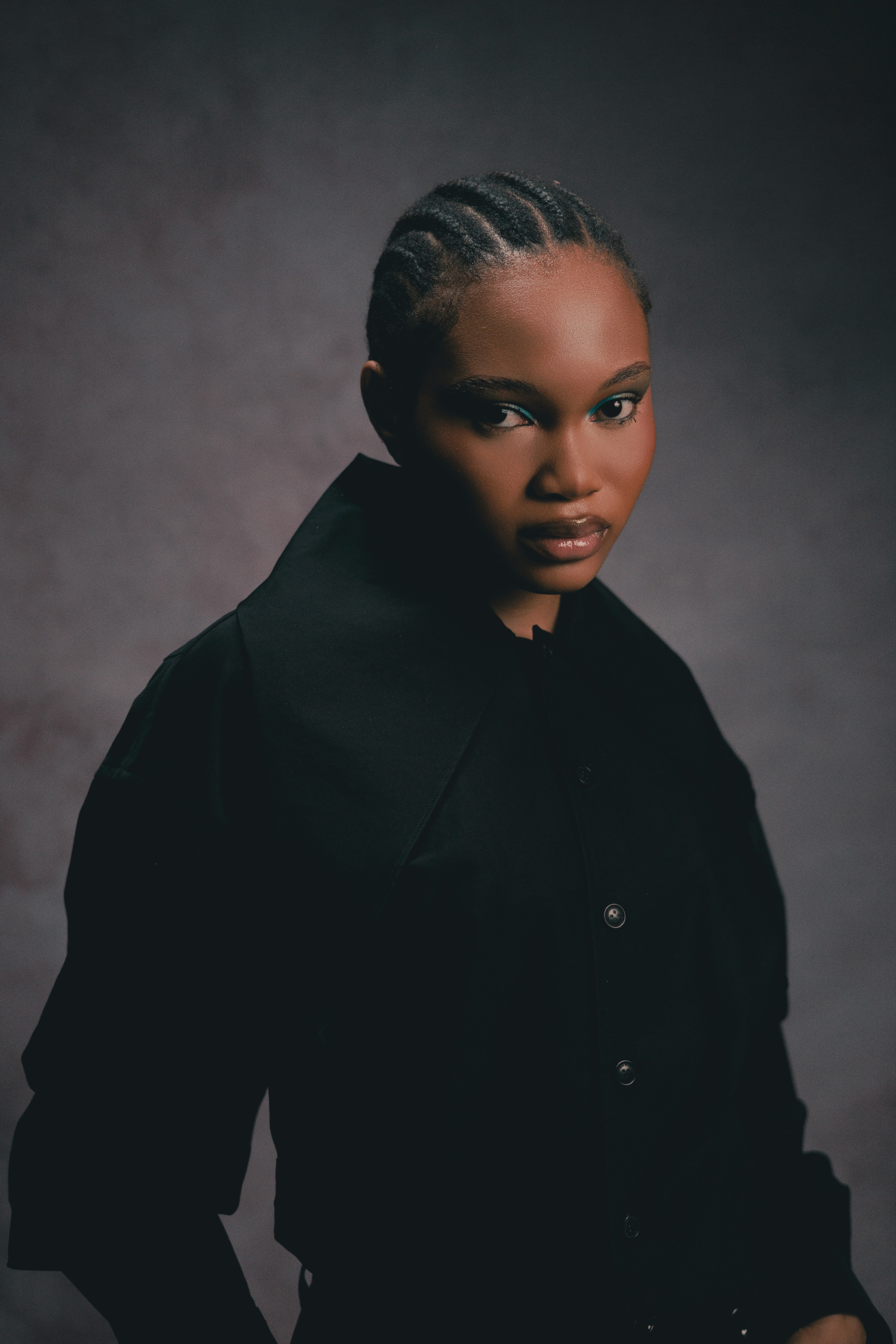 A young woman with braided hair in a black jacket.