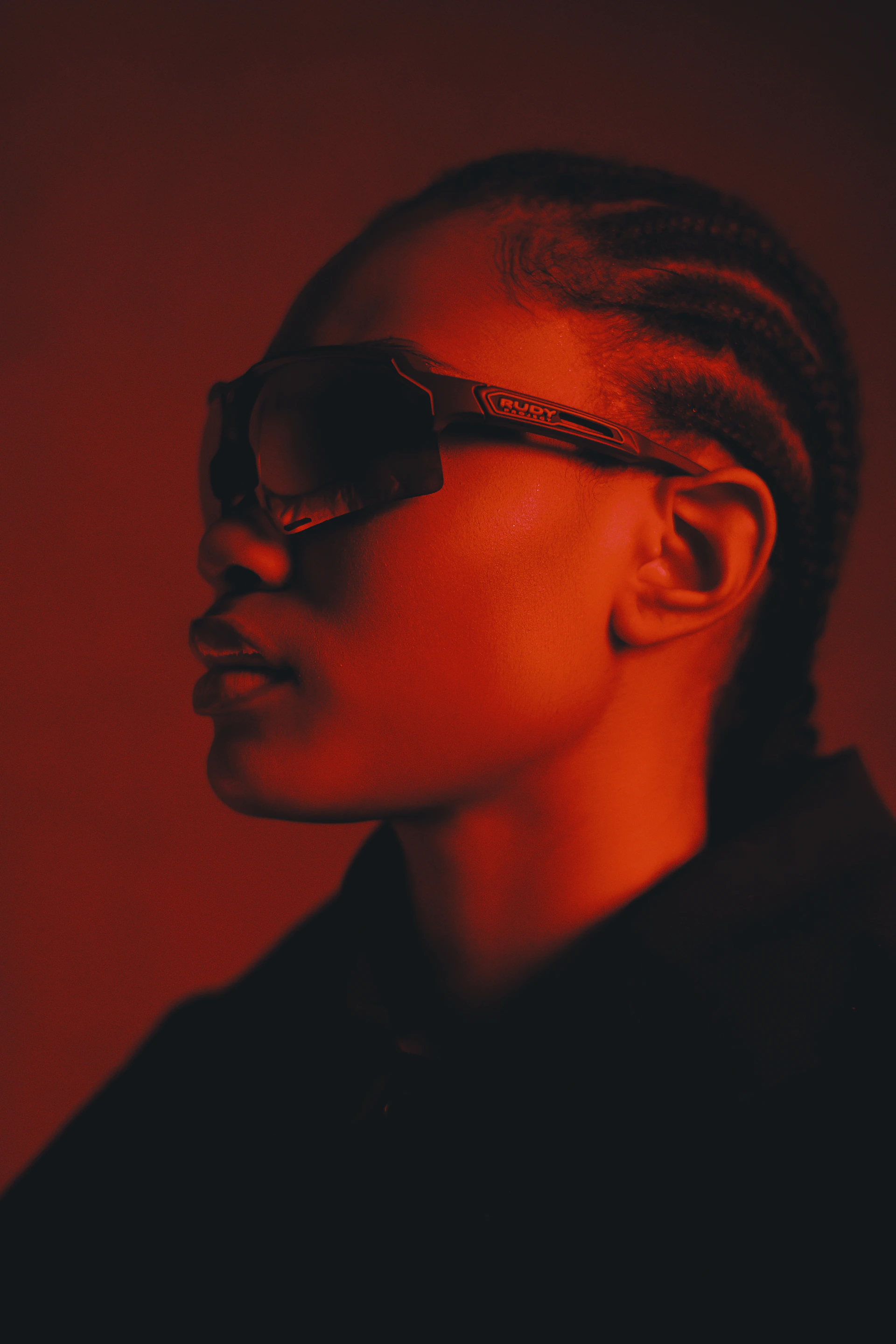 A person wearing sunglasses in red lighting