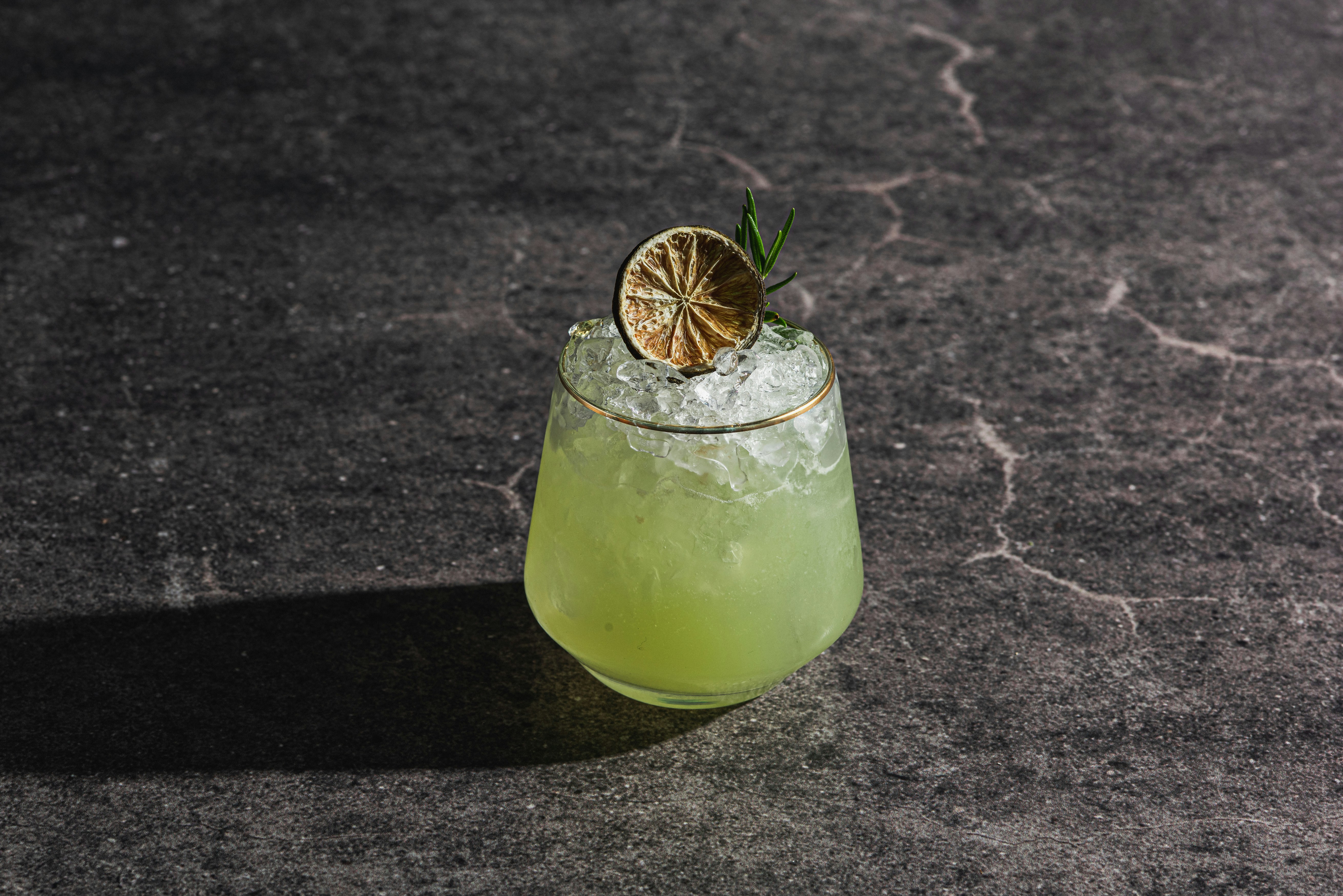 Un cocktail verde rinfrescante con ghiaccio e guarnizioni di lime