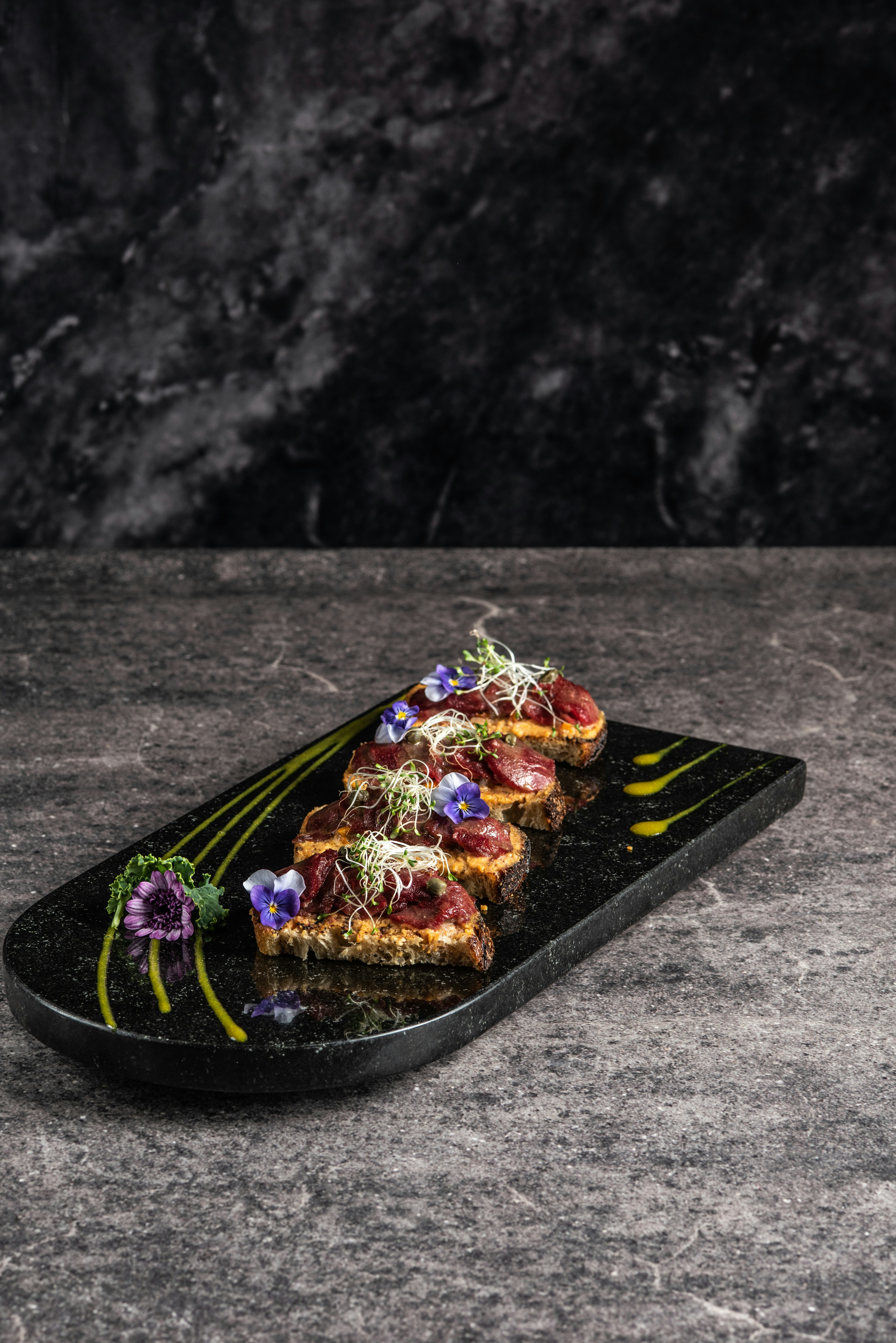 Morsi di tartare di tonno disposti con arte su un vassoio scuro