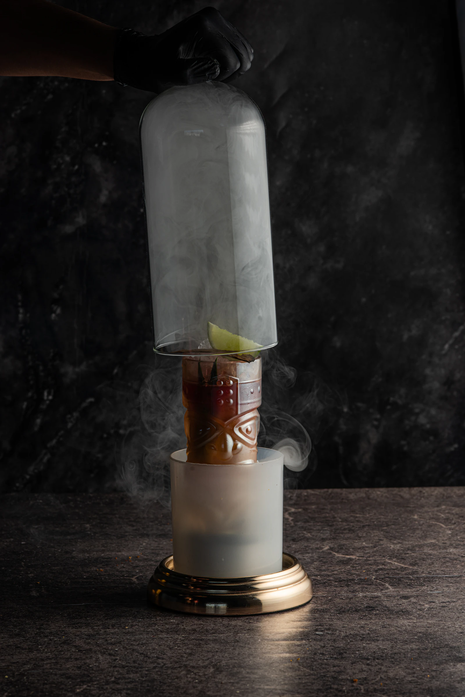 Smoked cocktail under a glass cloche with lime garnish