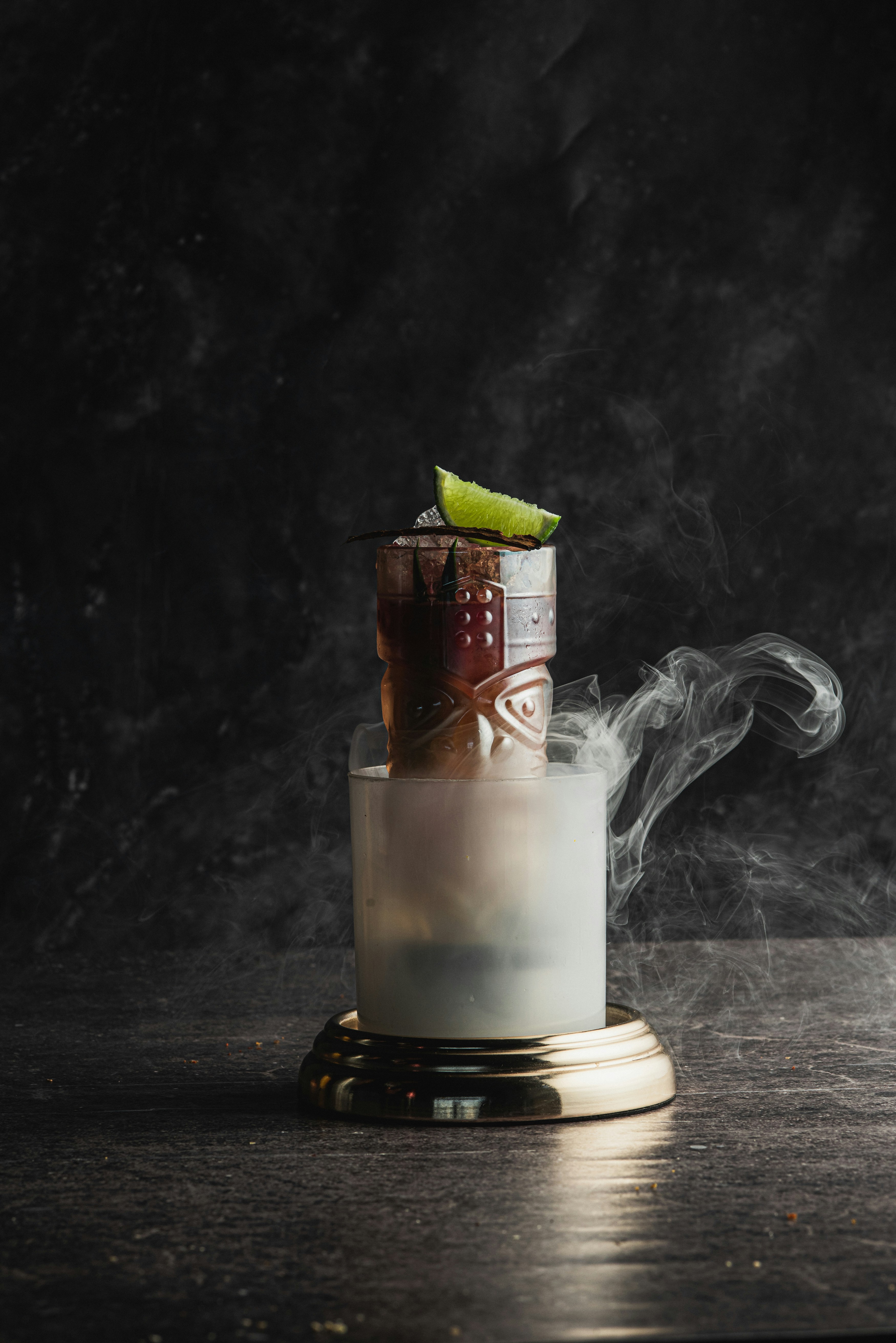 Cocktail affumicato con decorazione di lime su sfondo scuro