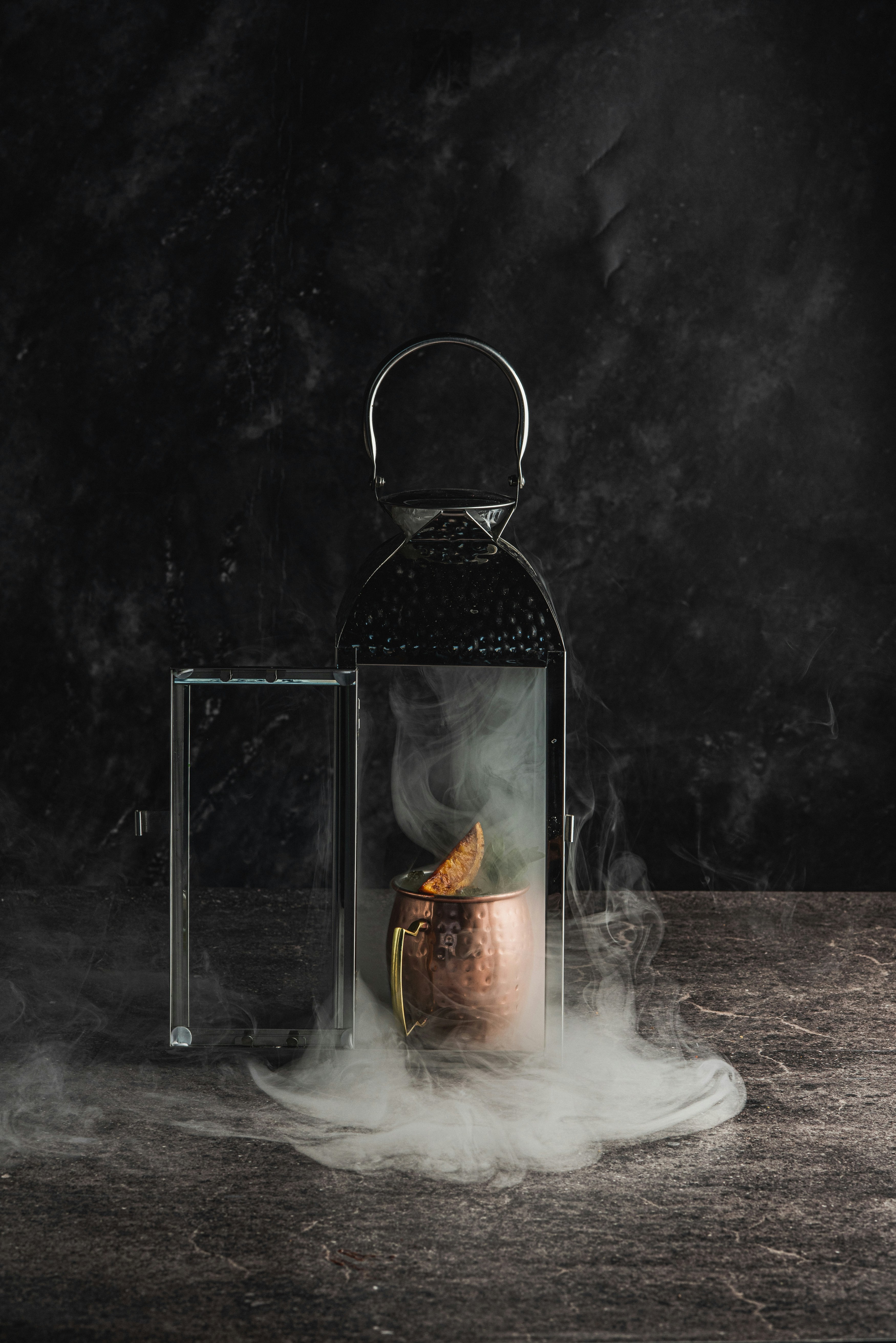 Cocktail affumicato in una tazza di rame dentro una lanterna