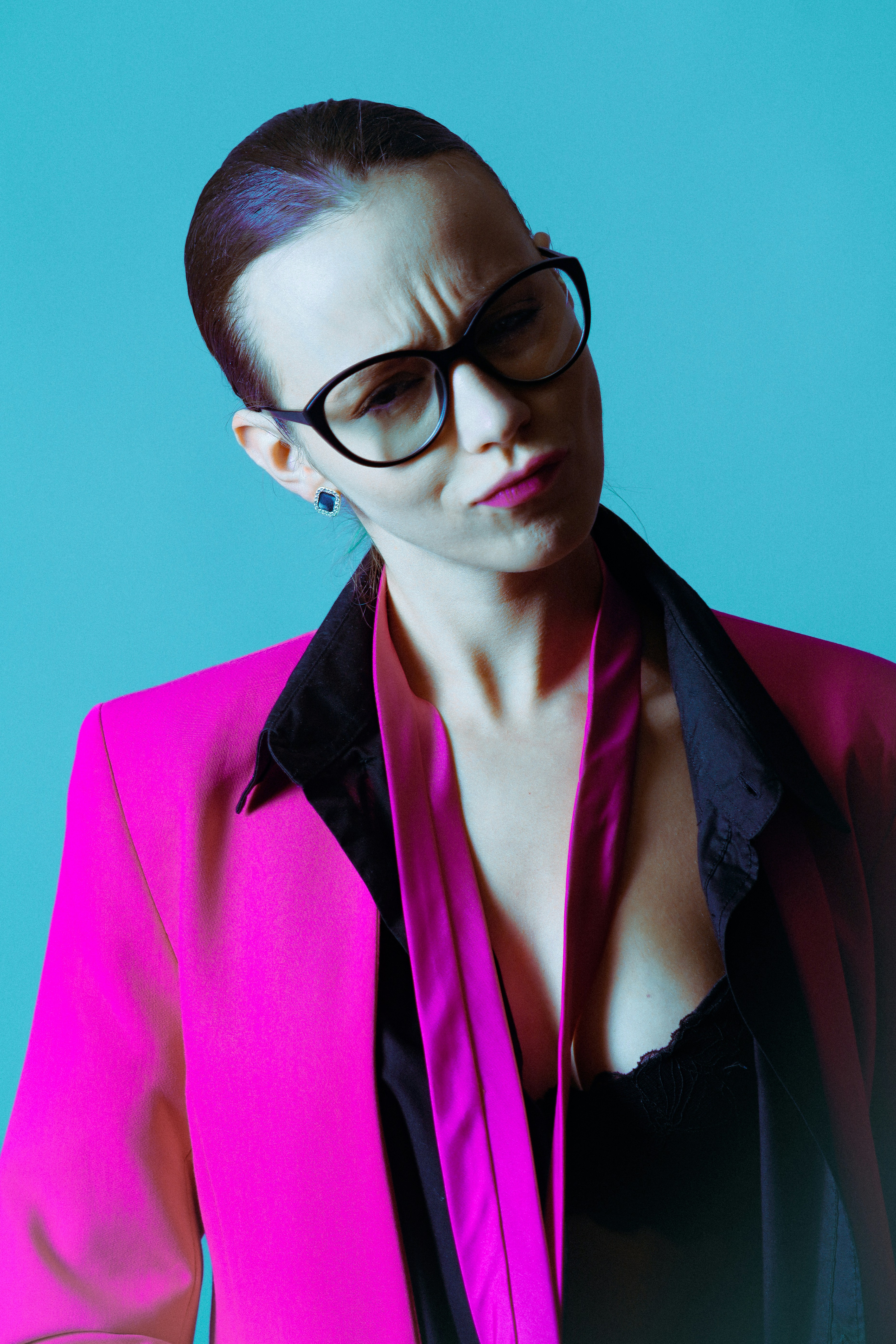 Frau im pinken Blazer mit Brille, sieht verwirrt aus