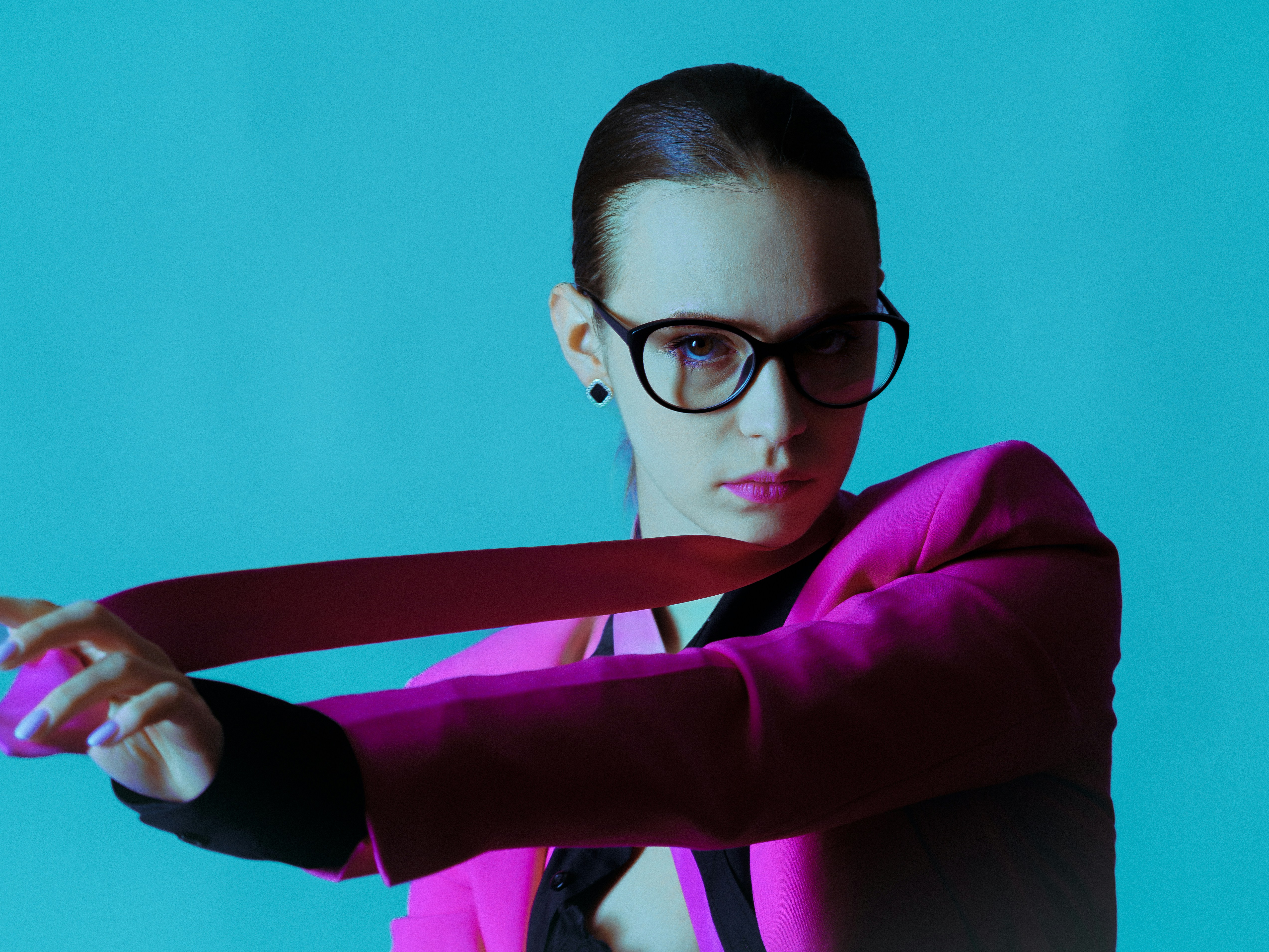 Frau mit rosa Jacke und Brille richtet die Krawatte