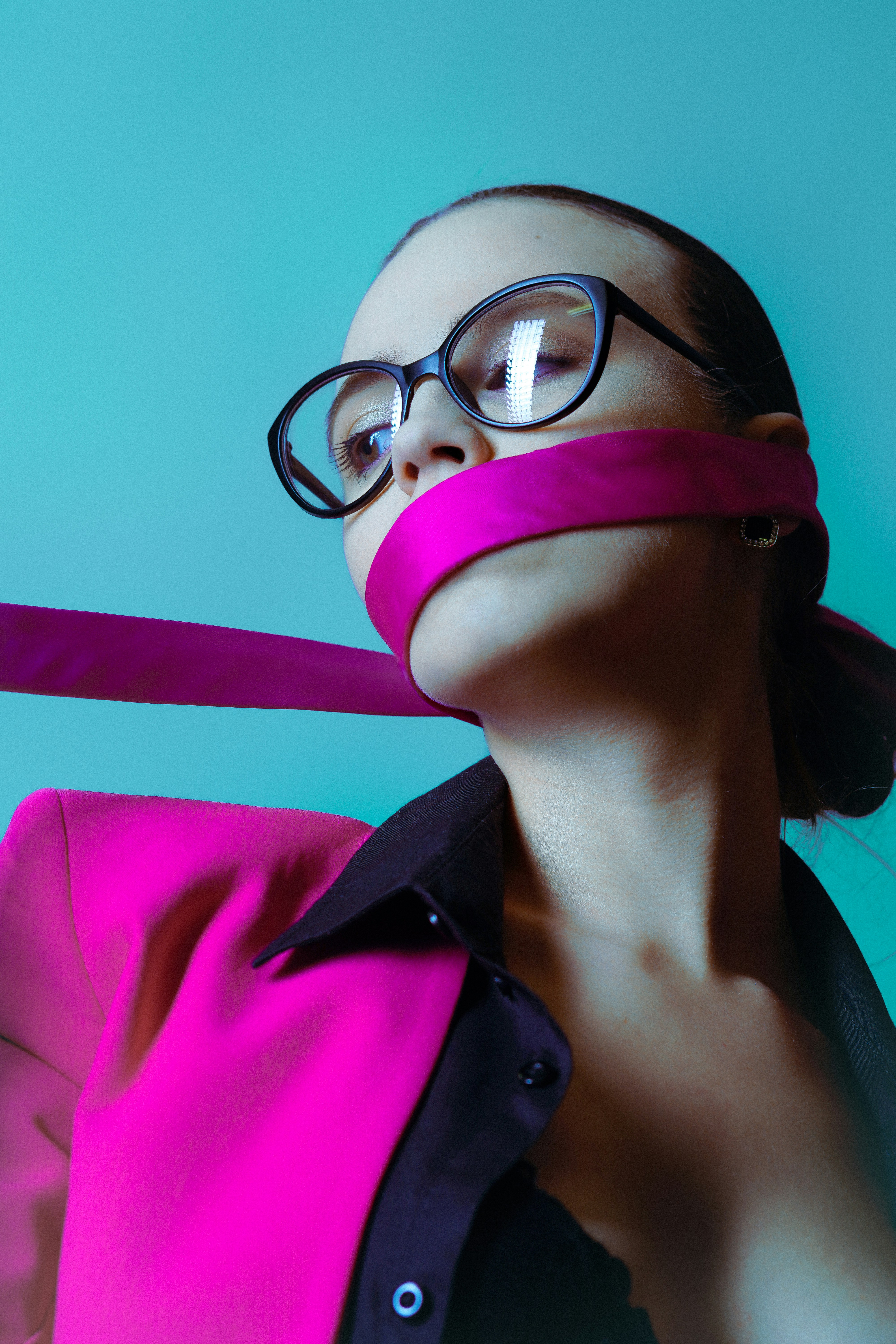 Frau mit rosa Band über dem Mund und Brille