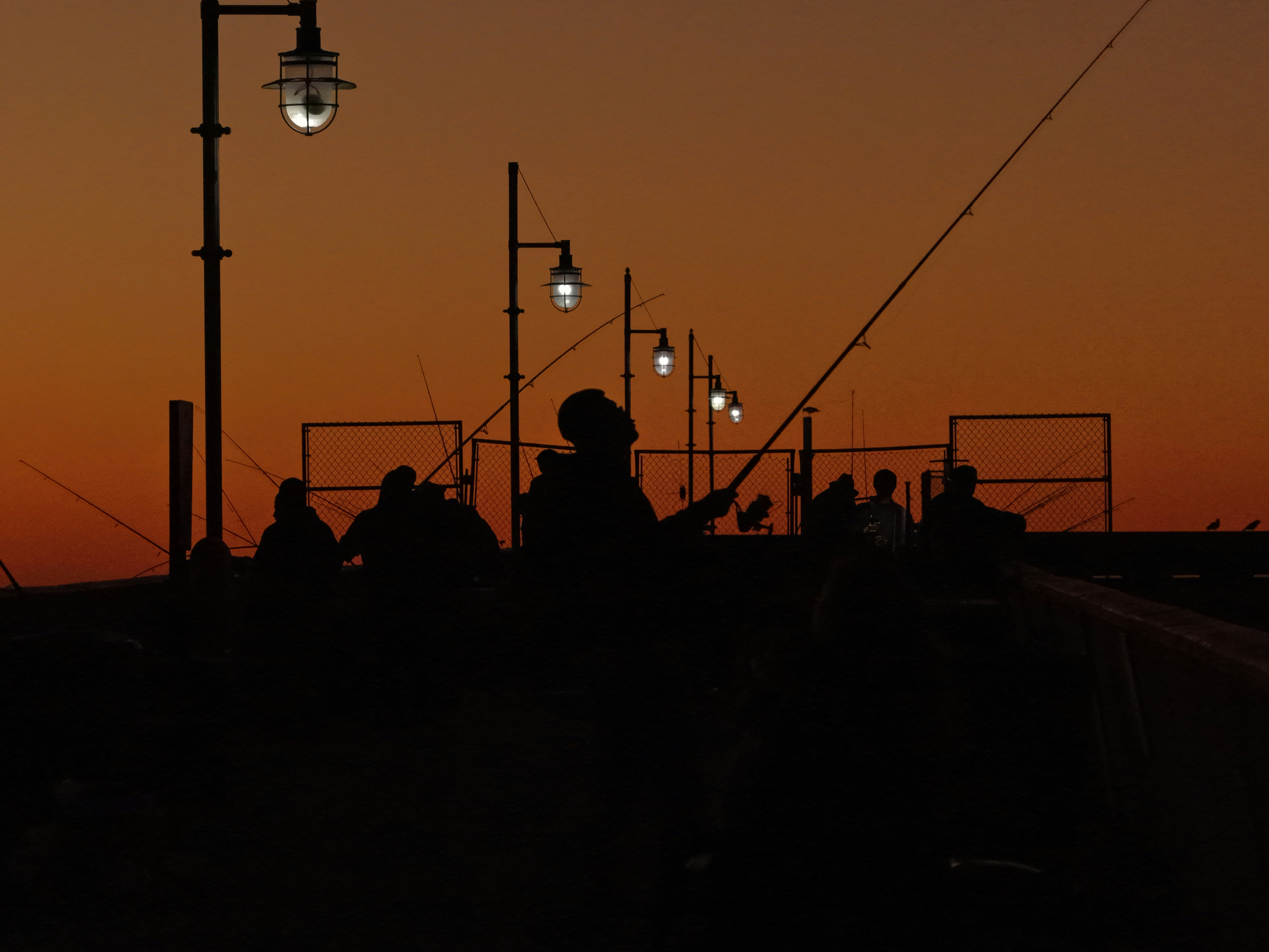 Pescadores en un muelle al atardecer con lámparas