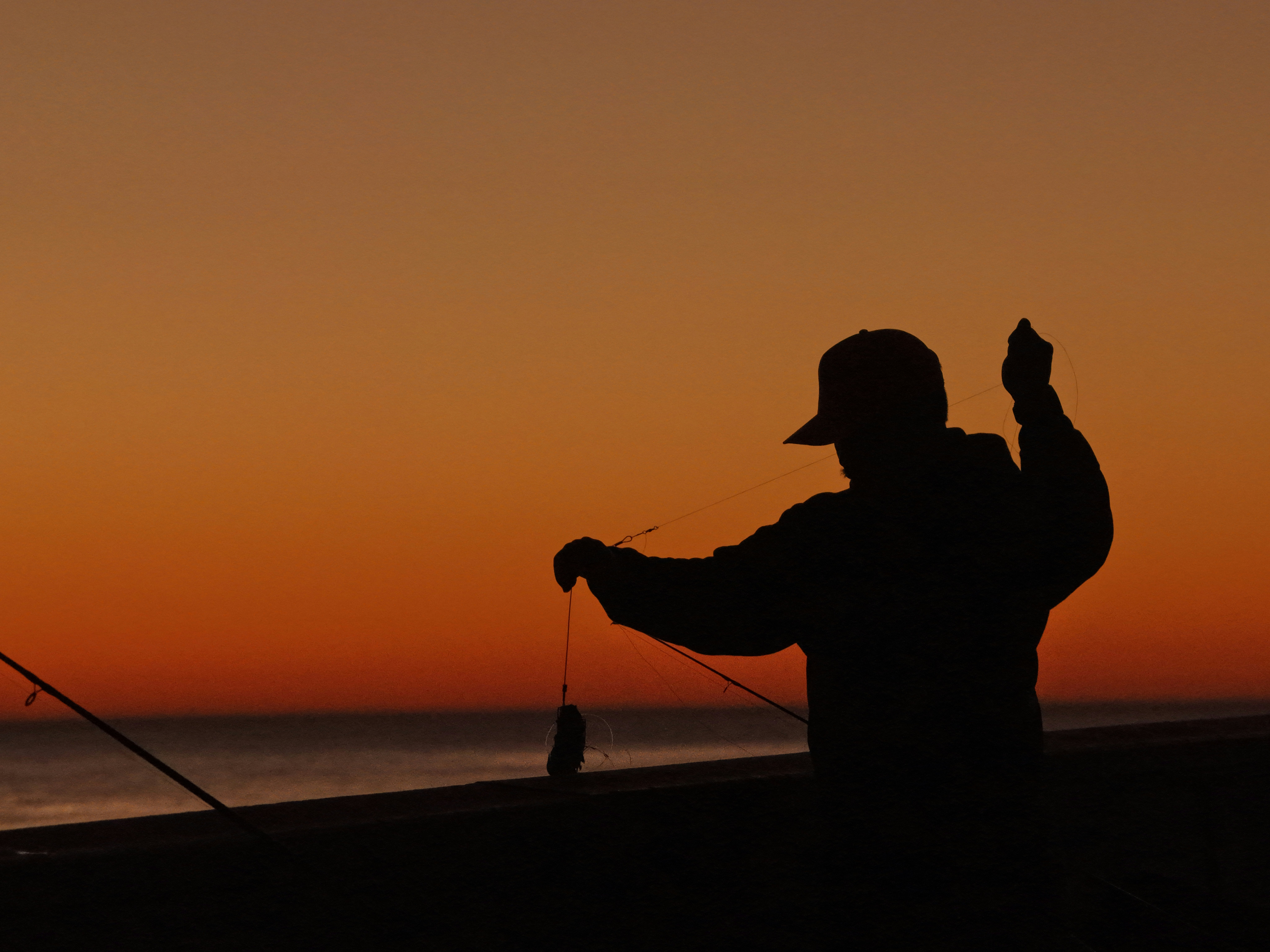 Silueta de una persona pescando al atardecer