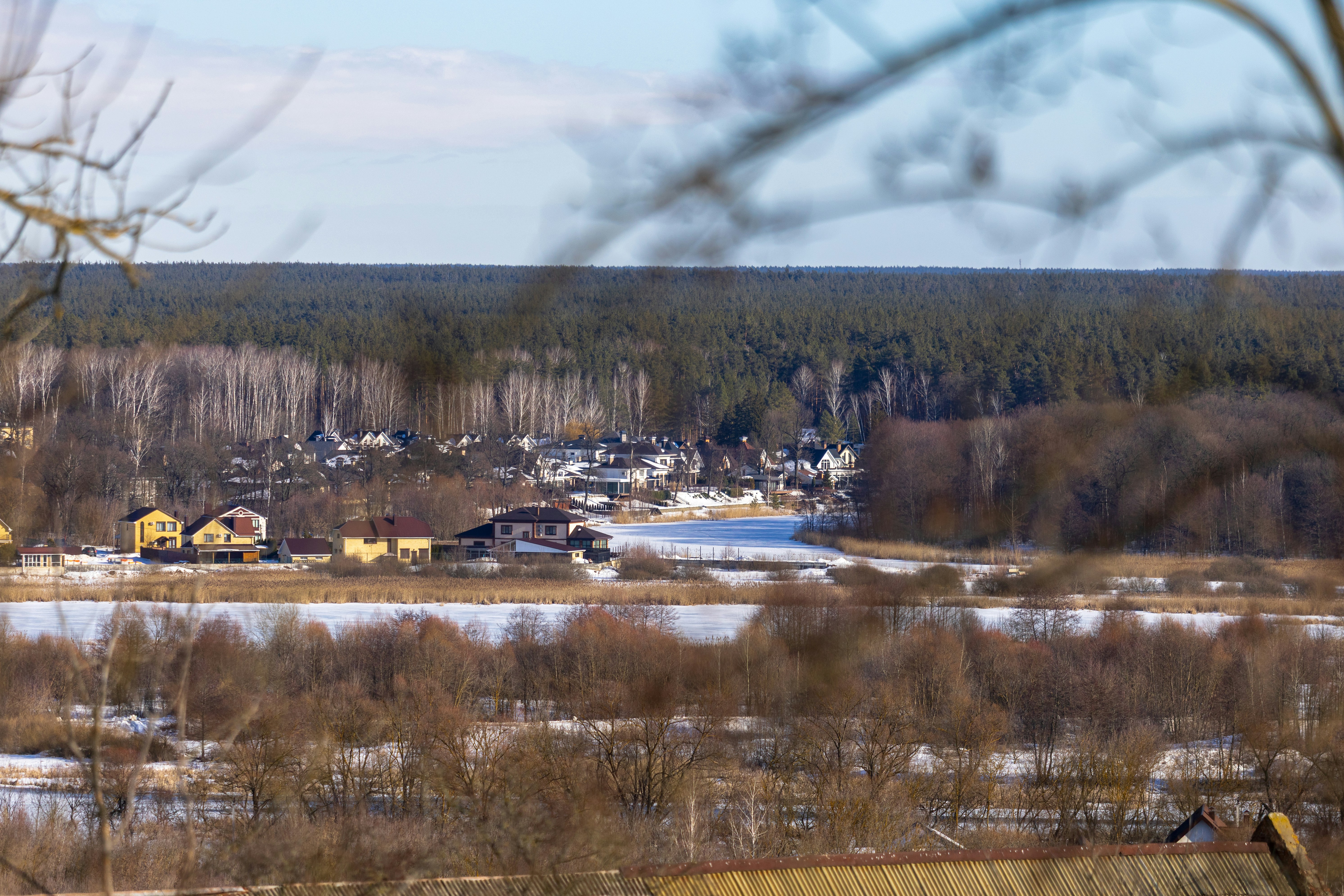 Entferntes Dorf, eingebettet zwischen Bäumen mit einem zugefrorenen See