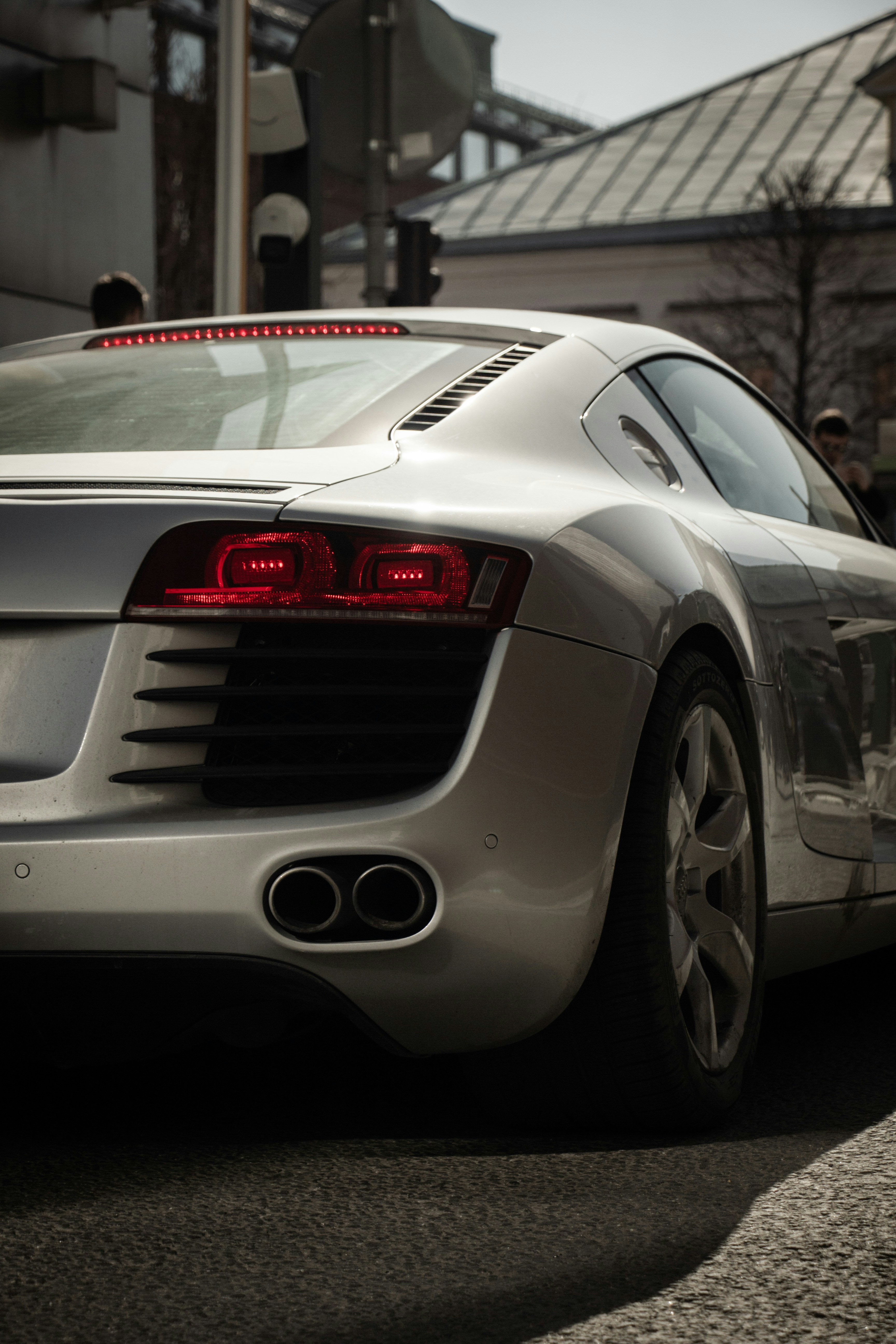 Silver sports car with red taillights parked on street