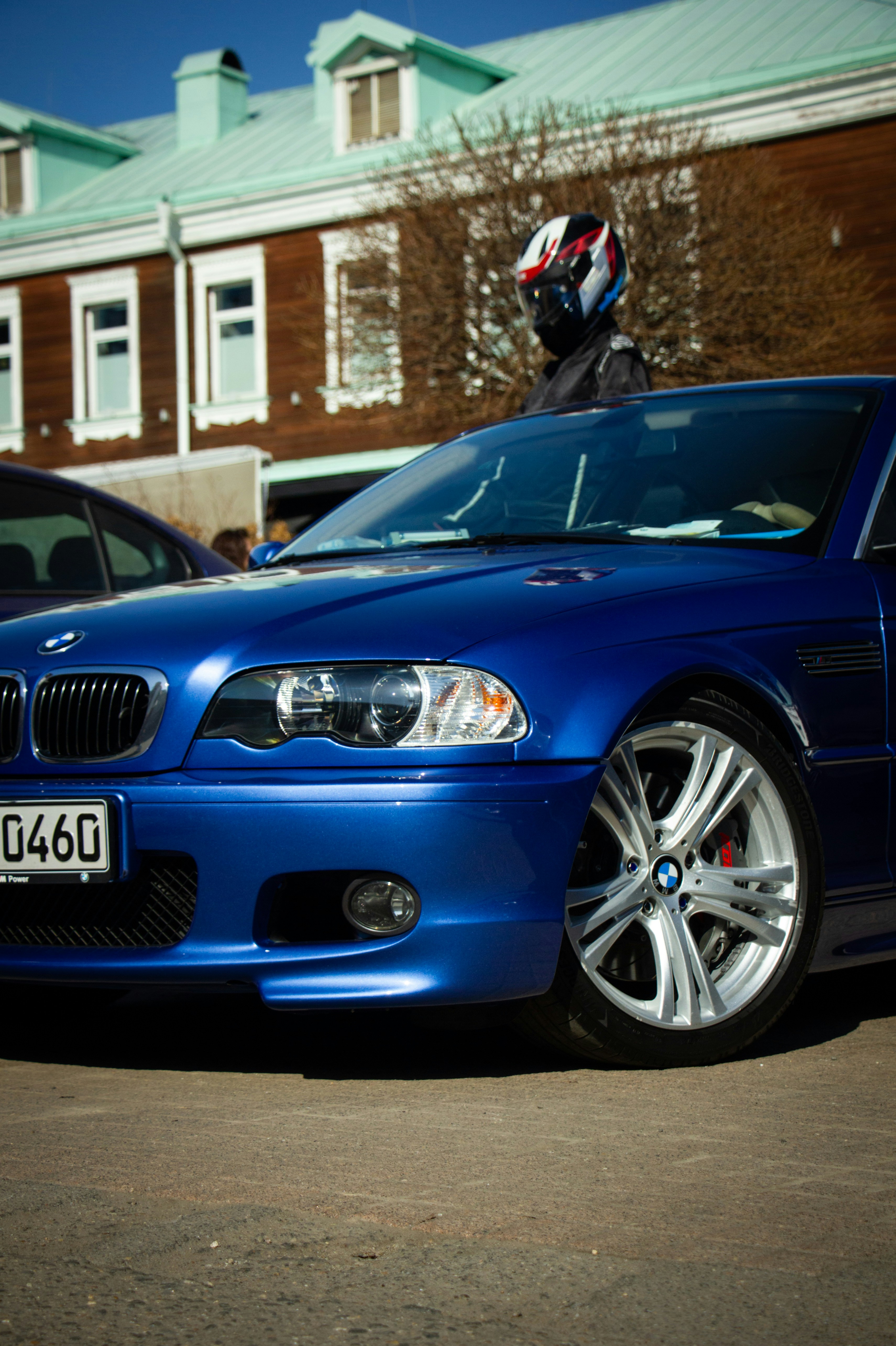 Blue BMW with a person in helmet standing behind it.