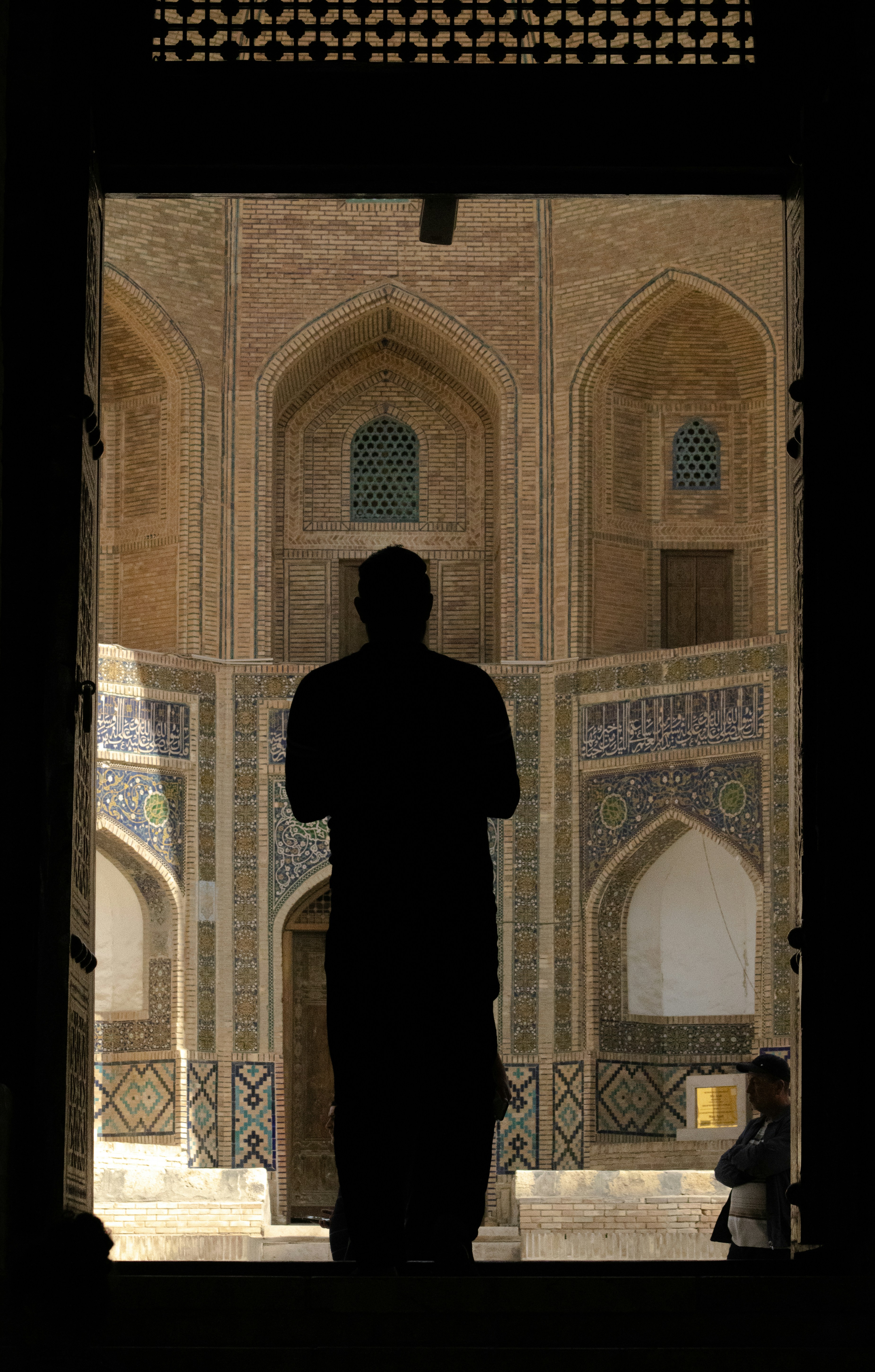 Silhouette d’un homme contre une architecture de mosquée ornée.
