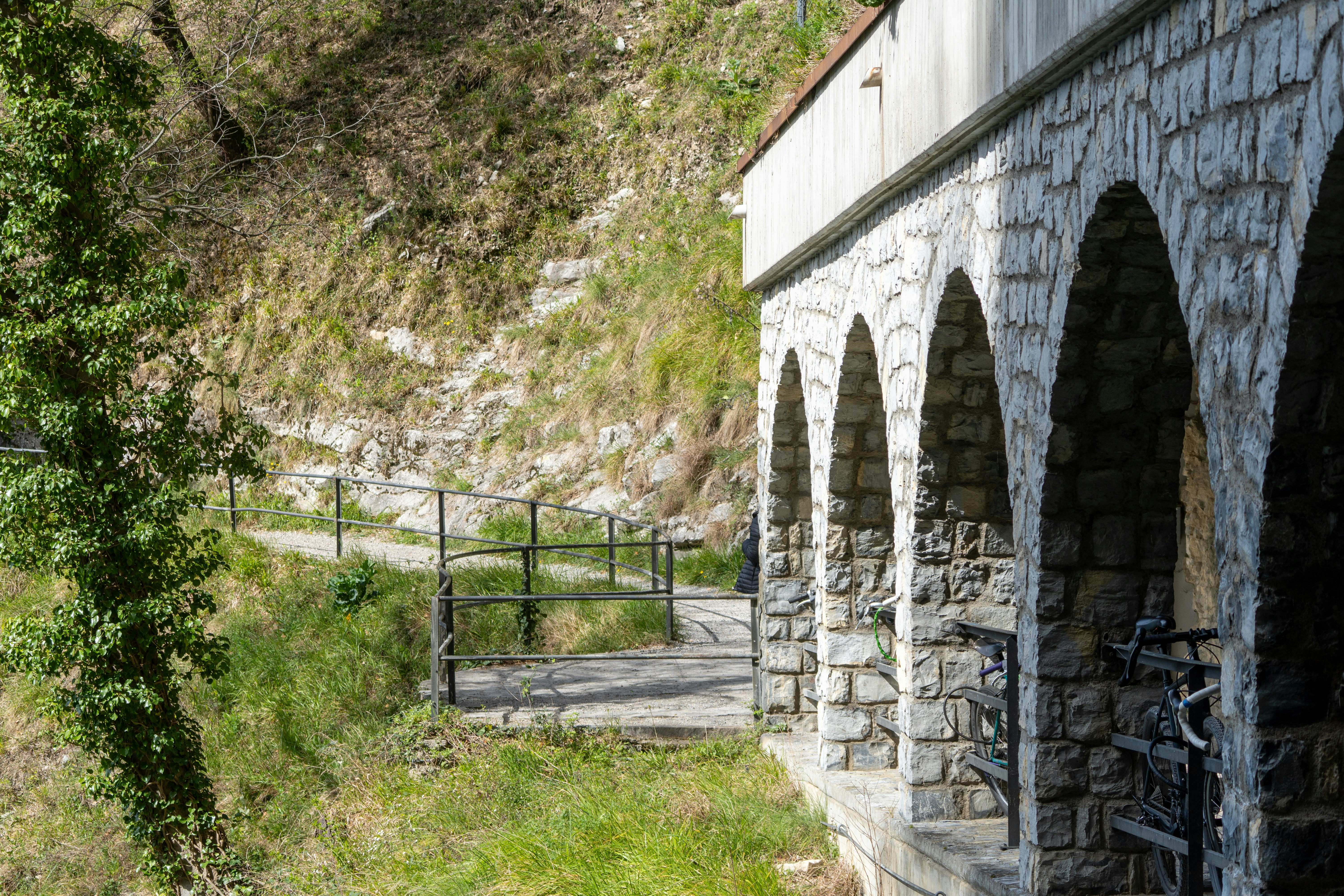 Stone arches of a building beside a grassy path