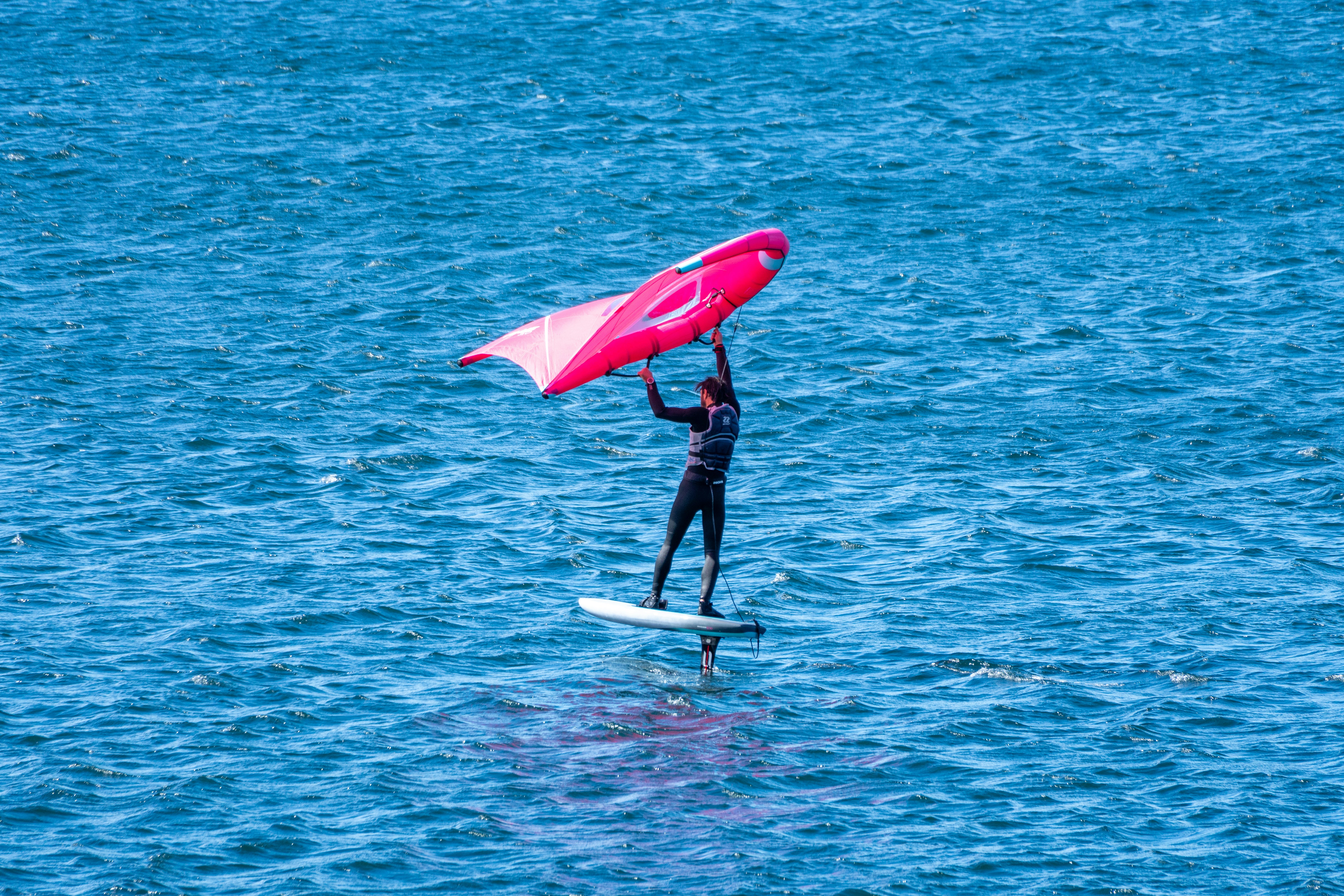 Person wing foiling on a bright pink wing.