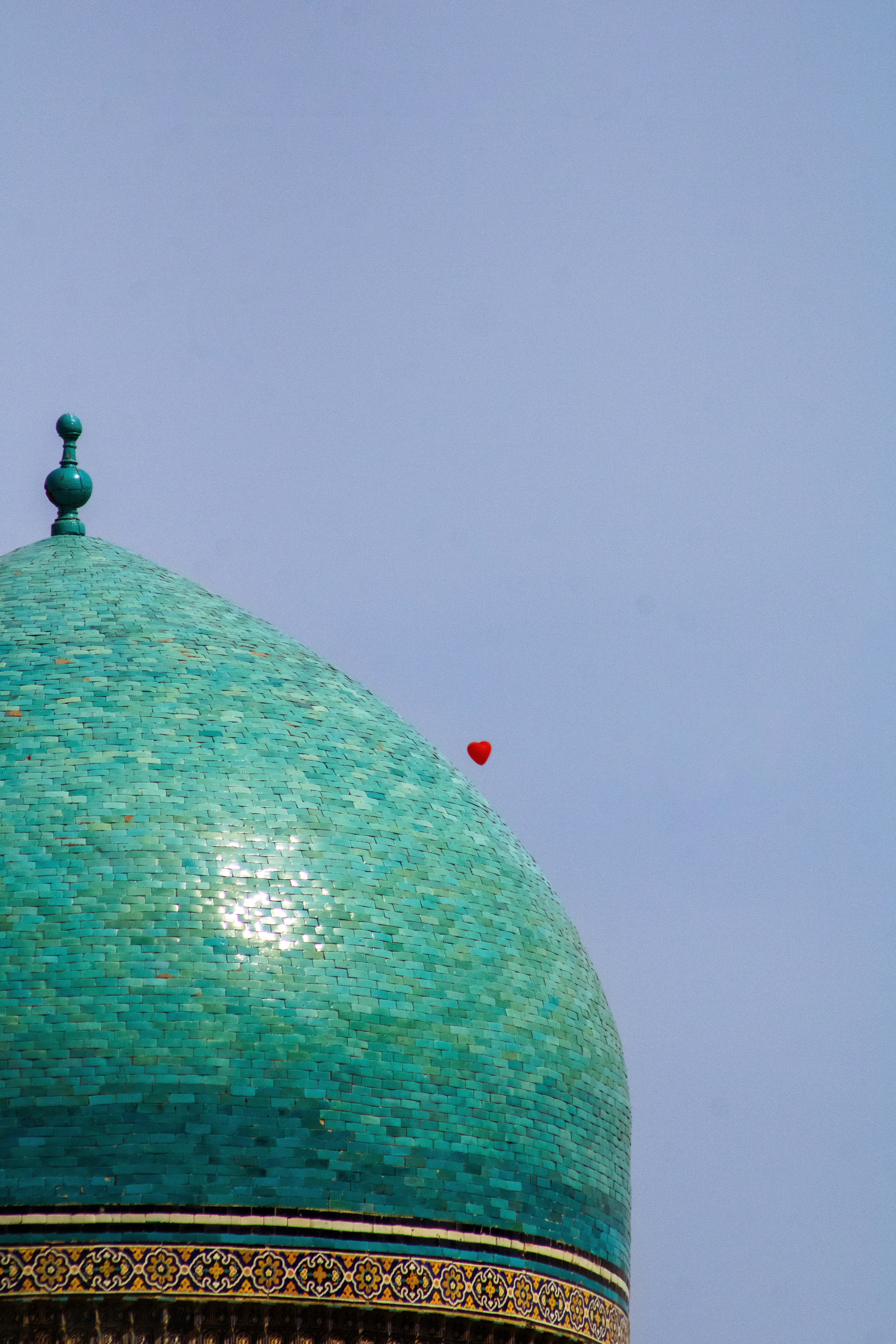 Dôme turquoise avec un petit ballon en forme de cœur rouge.