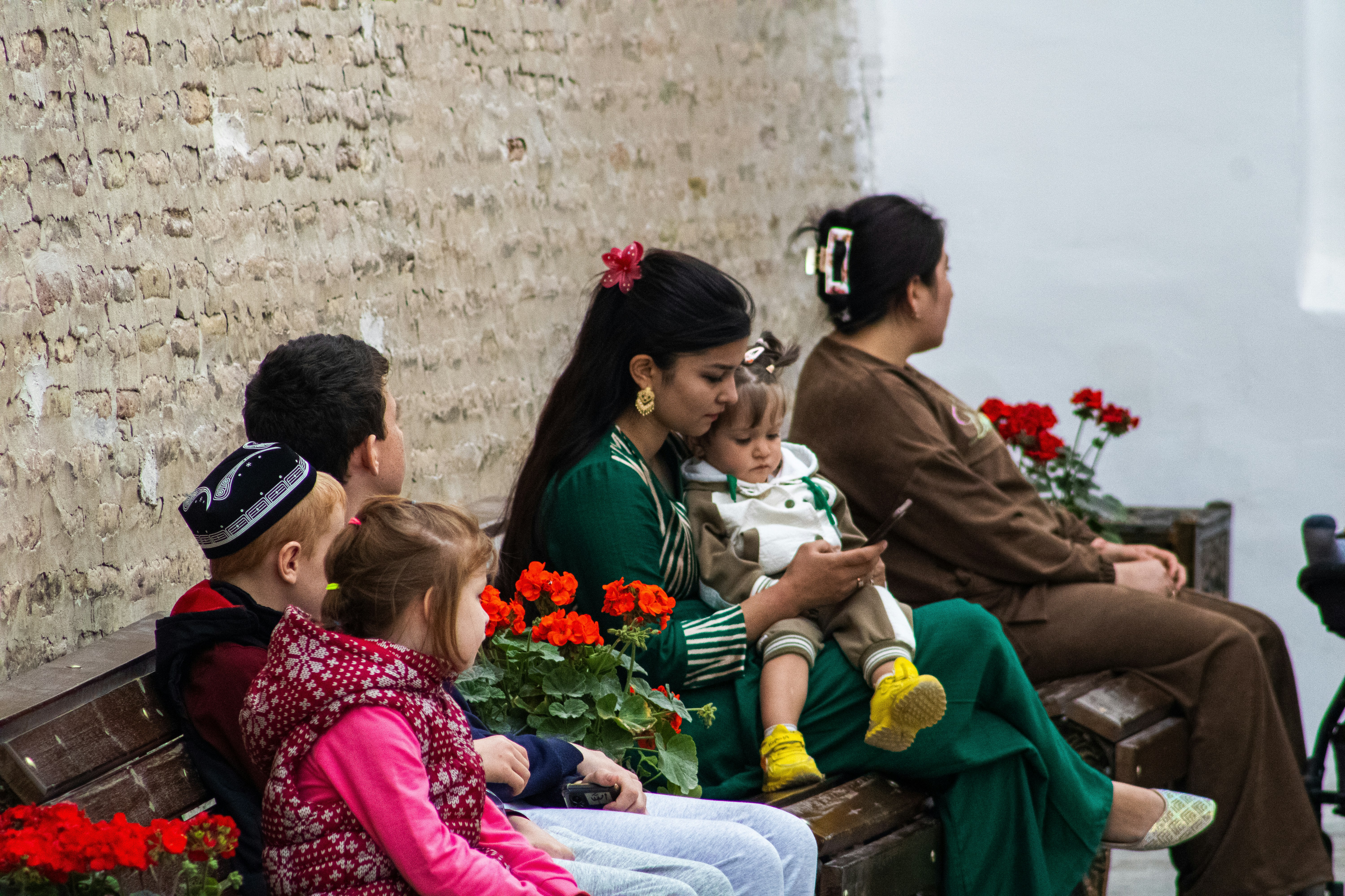 Une famille est assise sur un banc avec des fleurs.