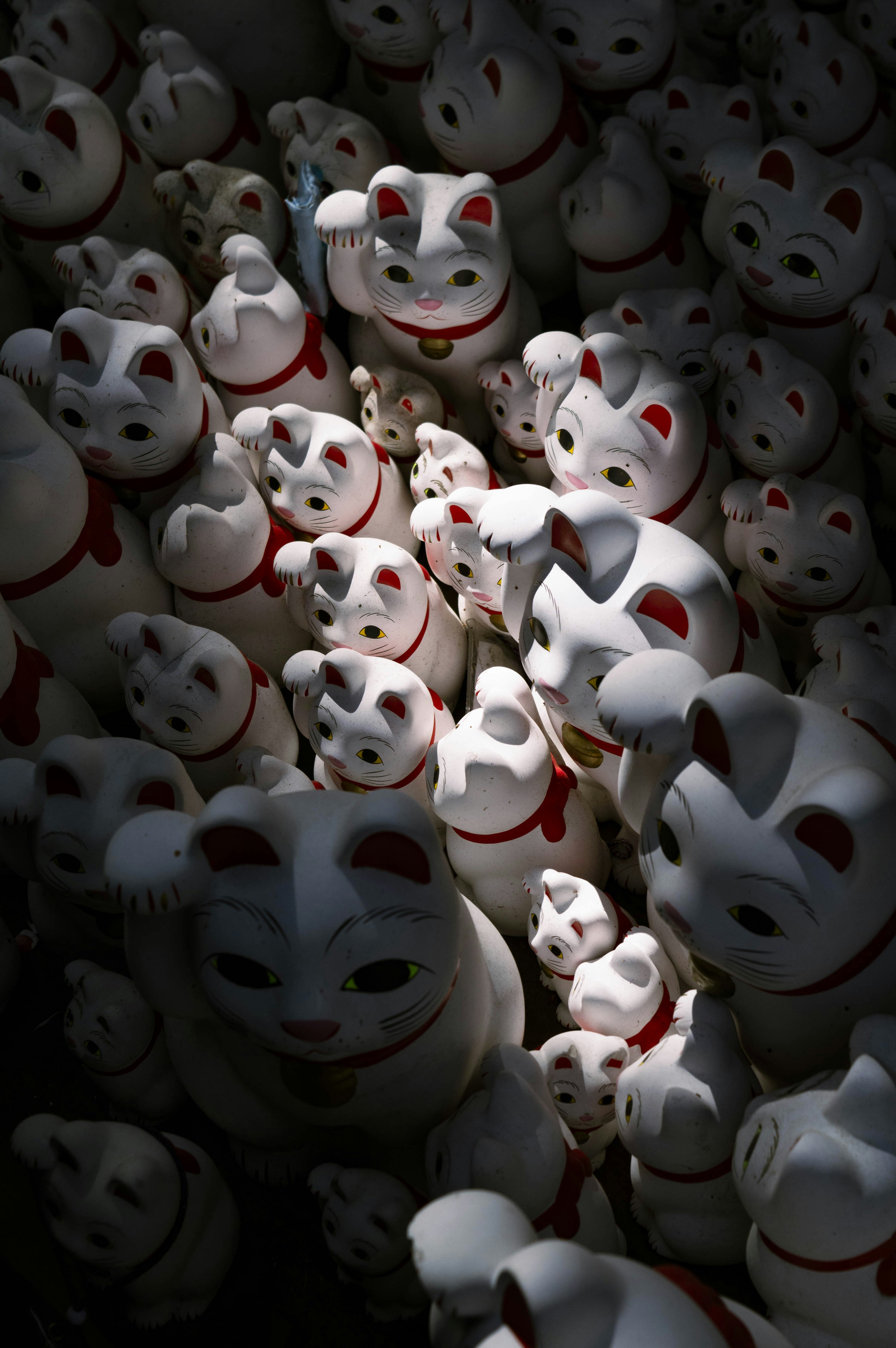 Eine Sammlung weißer Maneki-Neko-Statuen mit roten Kragen