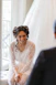 A smiling bride in a lace robe looks at someone