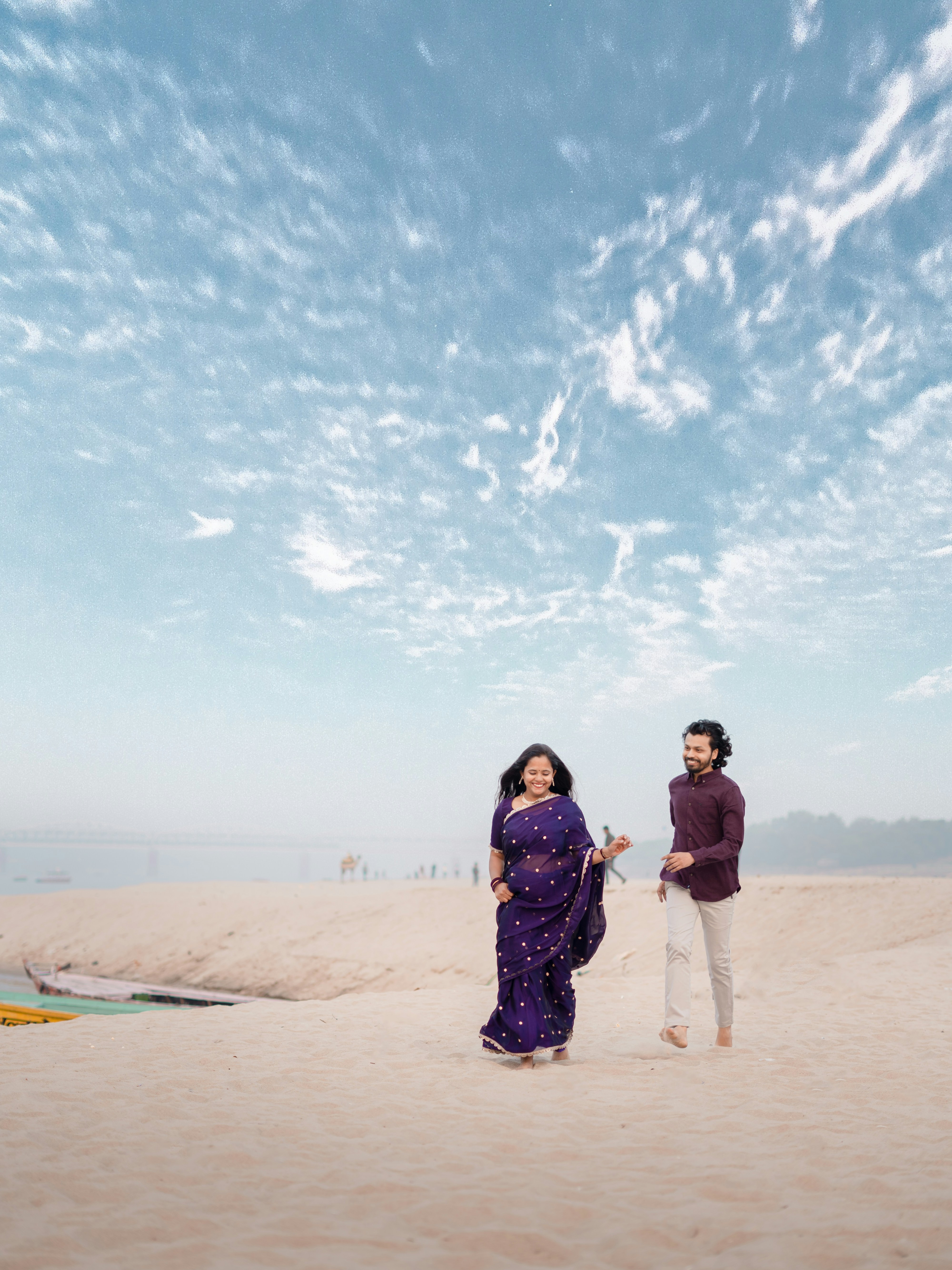 Paar geht an einem Sandstrand unter bewölktem Himmel